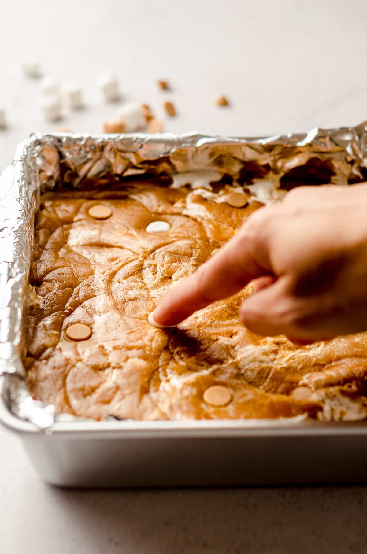 pushing mini marshmallows into the top of fluffernutter bar batter