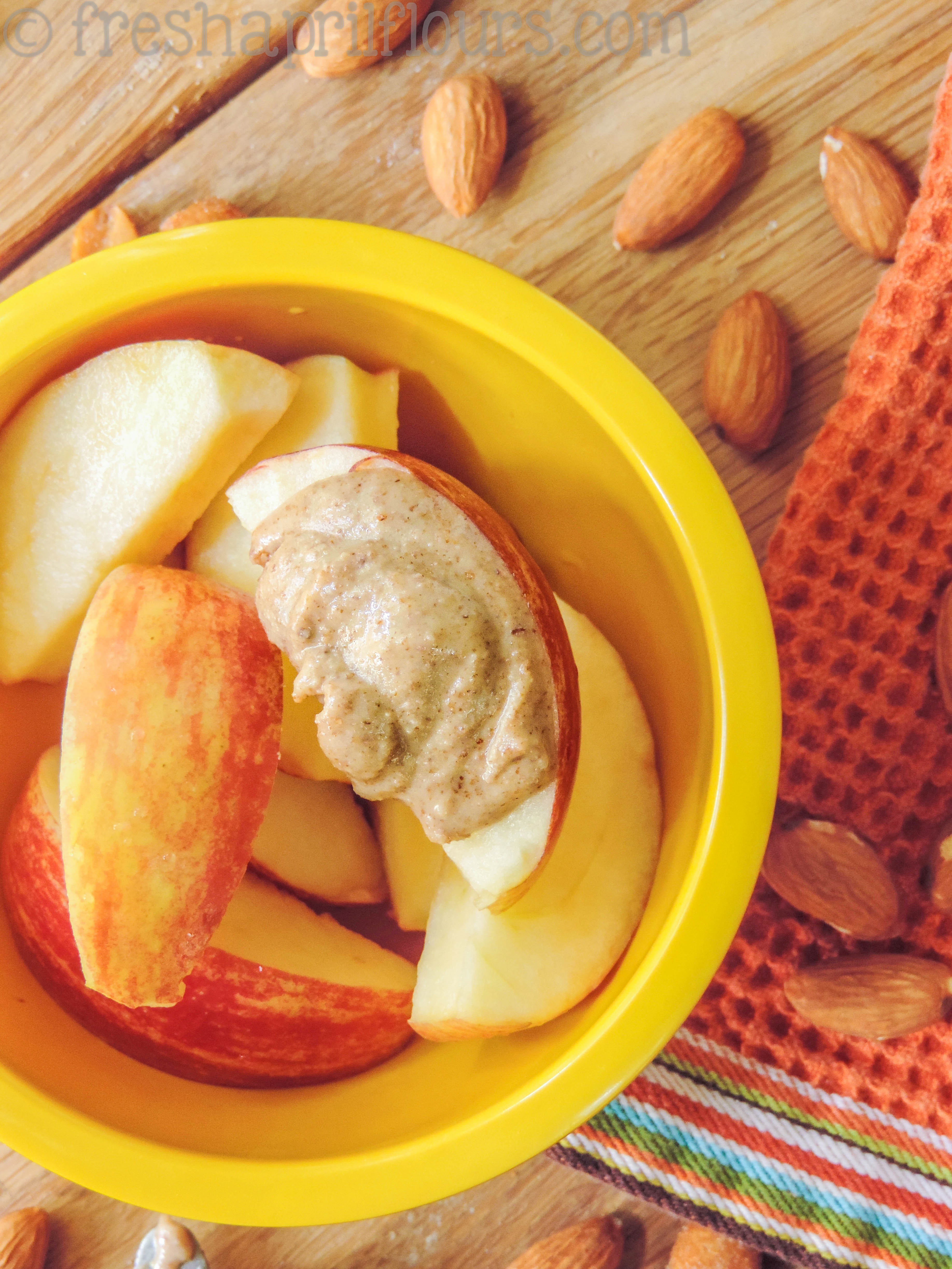 apples in a bowl with homemade almond butter spread on a slice
