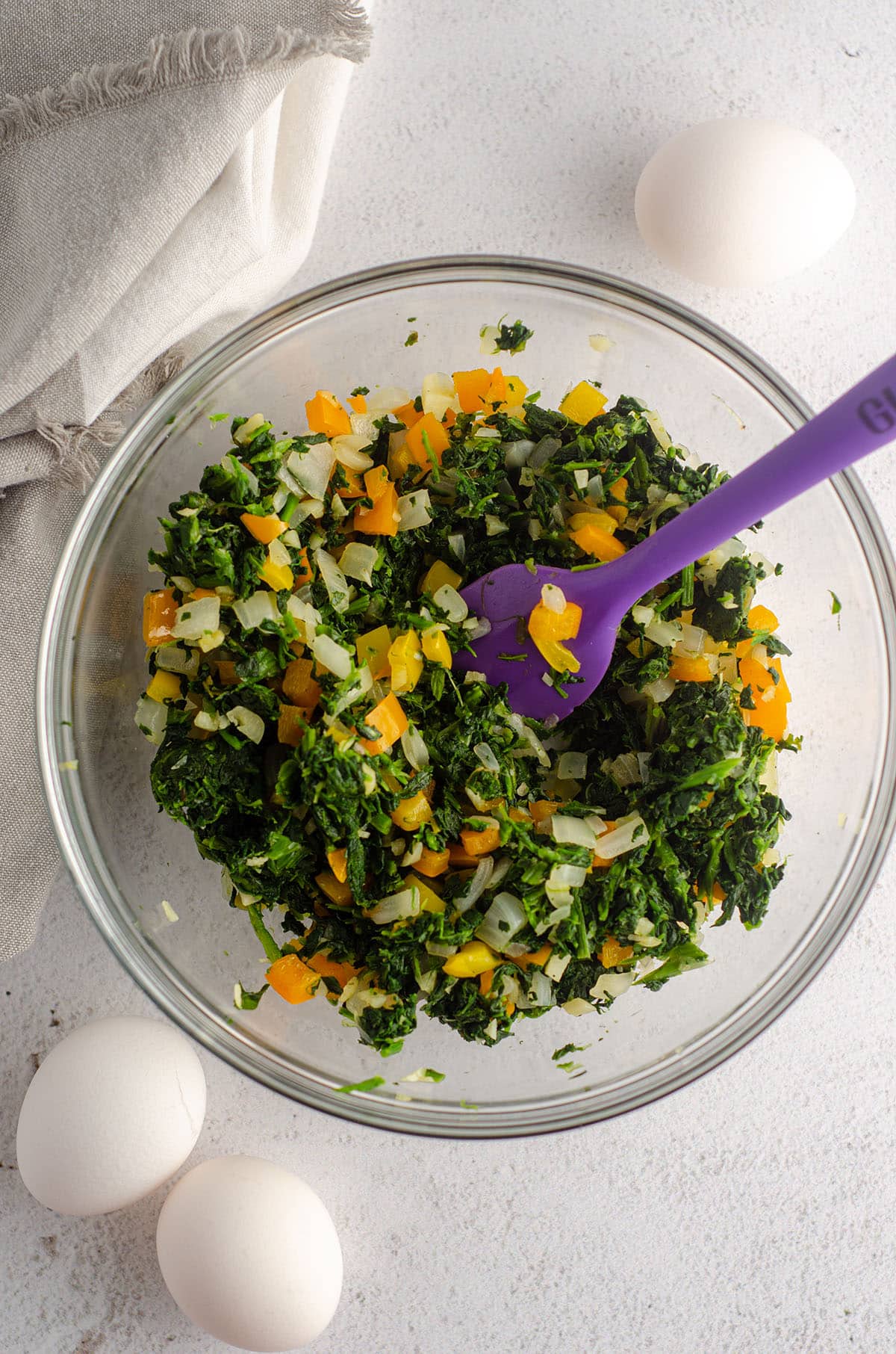 bowl of greens with chopped peppers and onions in a bowl ready to be the filling of a quiche