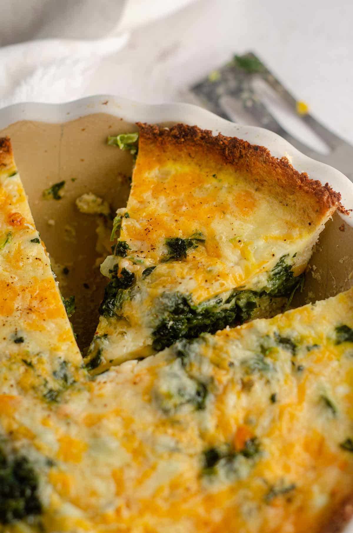 sliced cheesy vegetable quiche with cauliflower crust in a pie plate