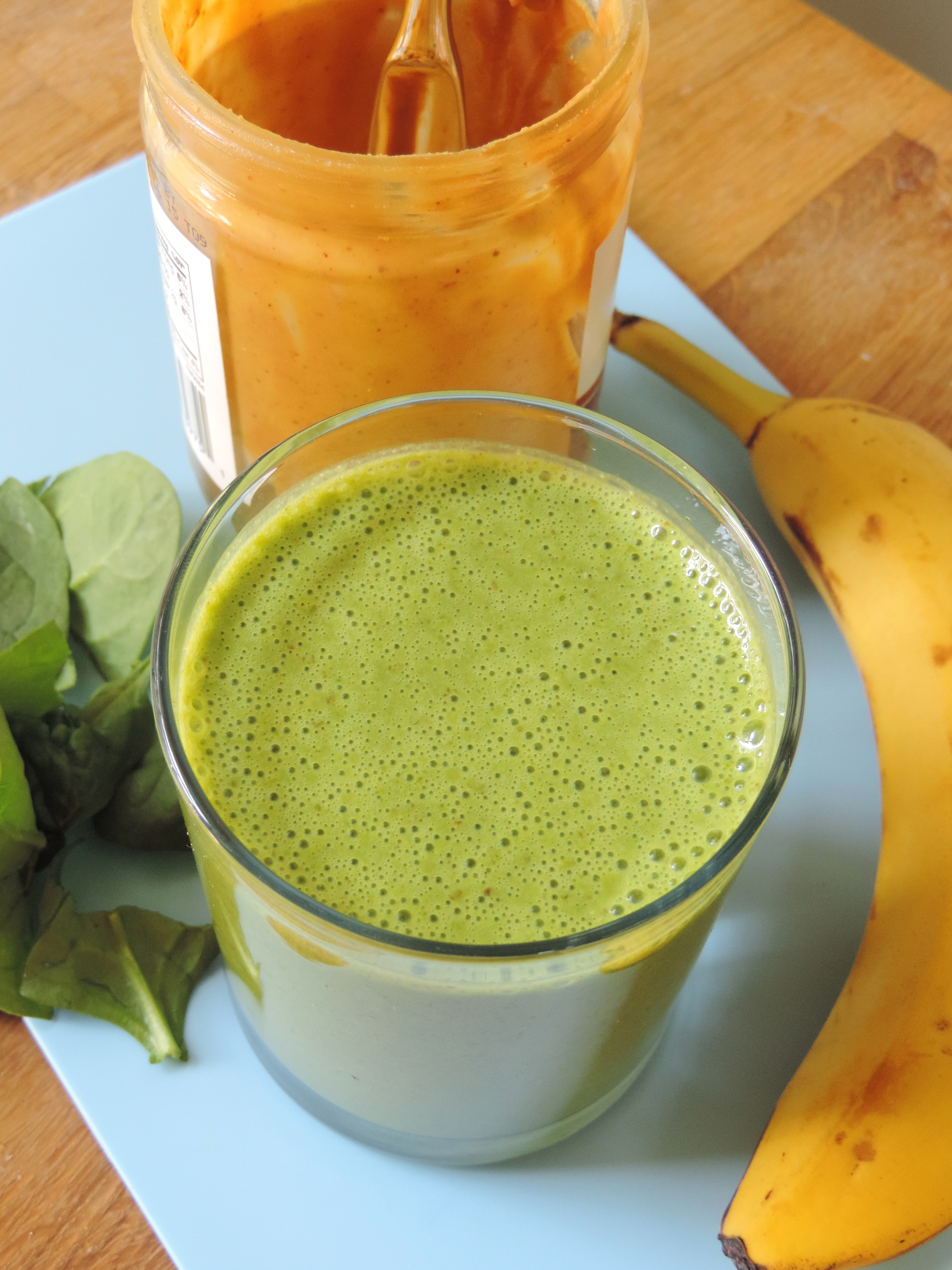 banana peanut butter smoothie in a cup with ingredients around it