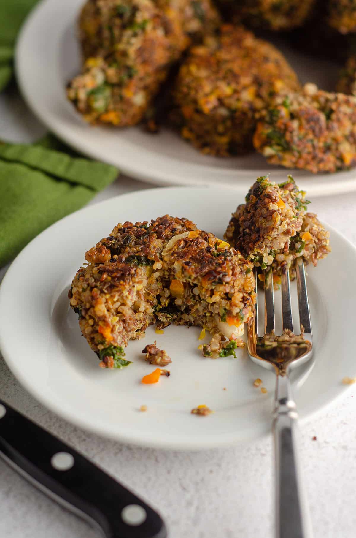 quinoa patty sitting on a plate with a bite taken out with a fork