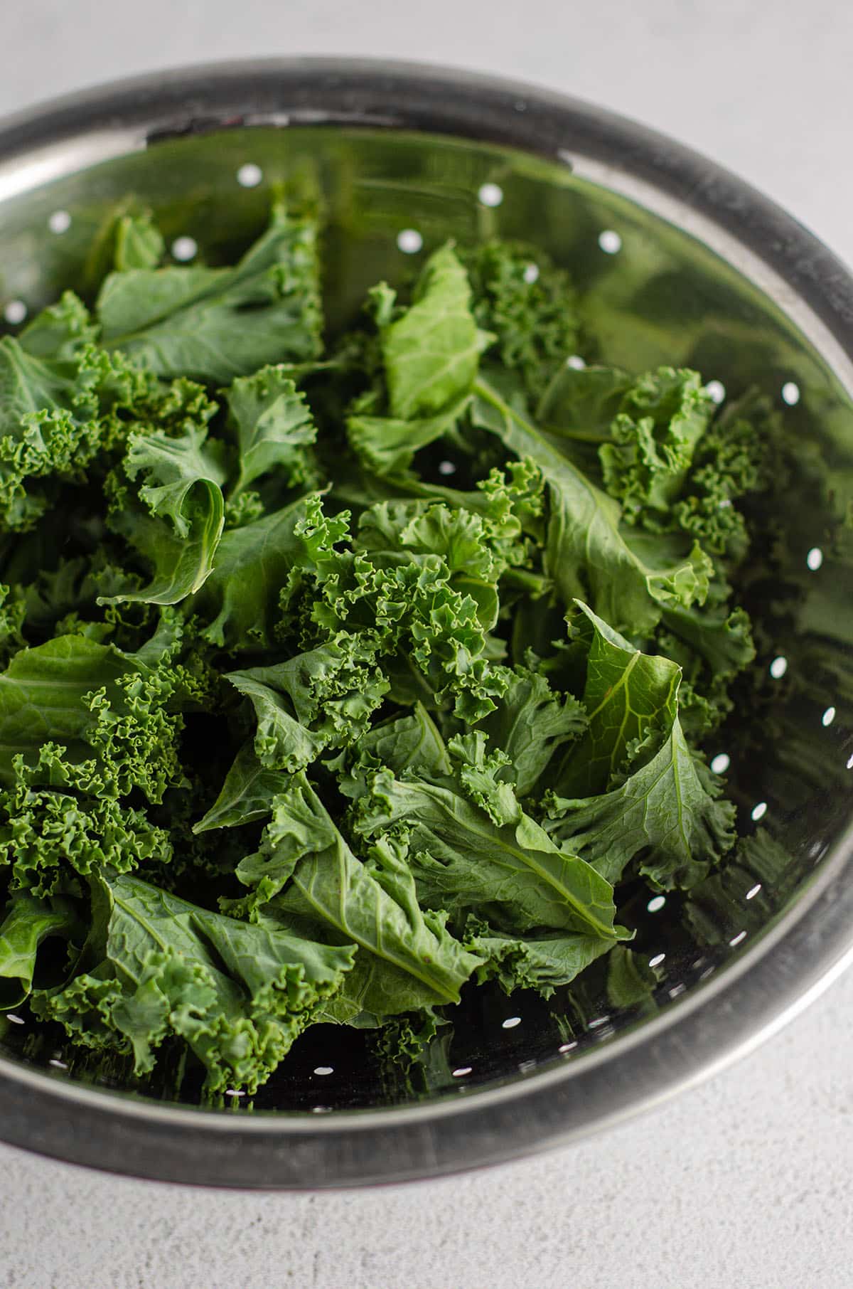 kale leaves sitting in a metal strainer