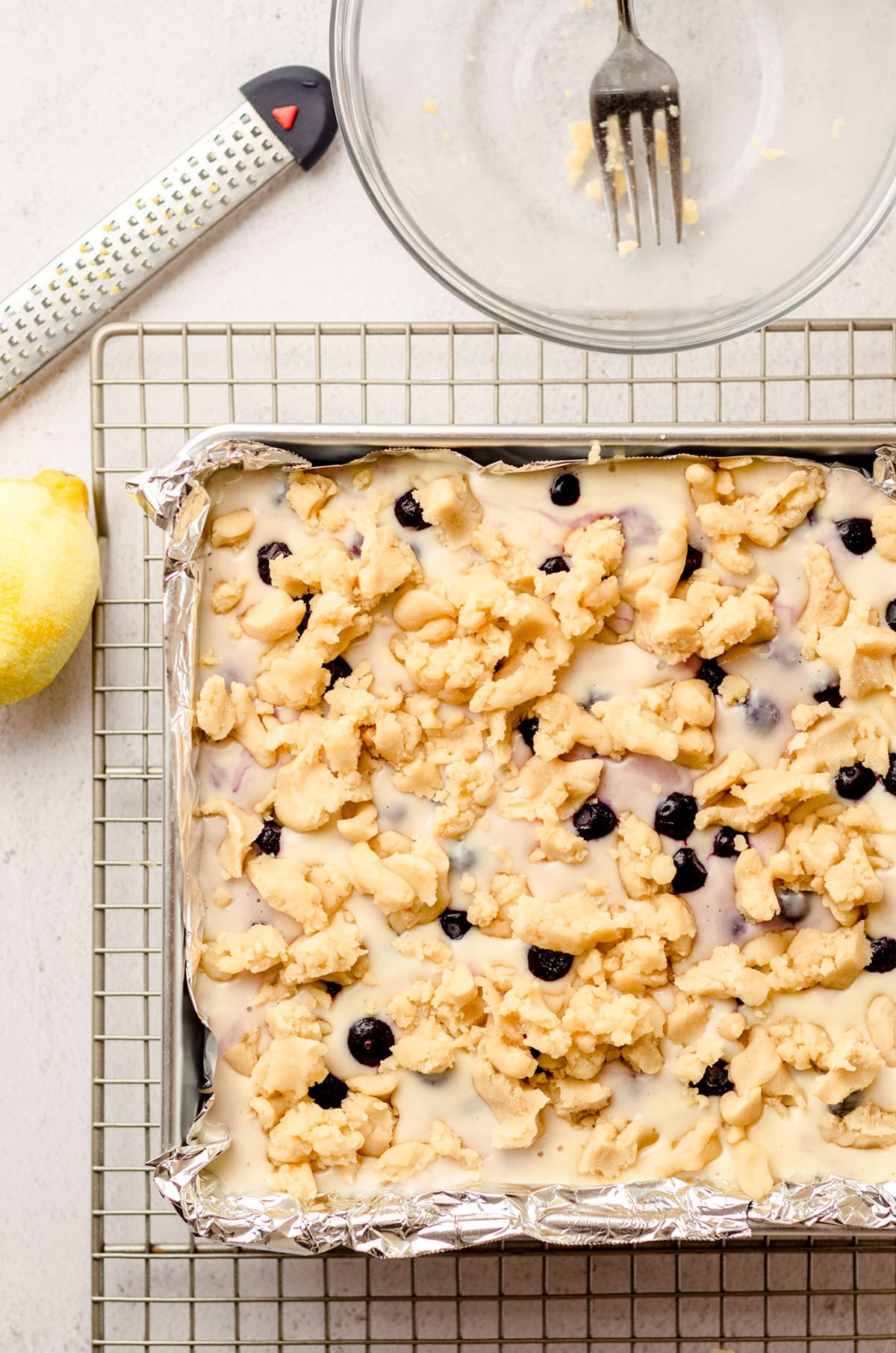 aerial photo of crumbles of shortbread crust onto blueberry lemon bars