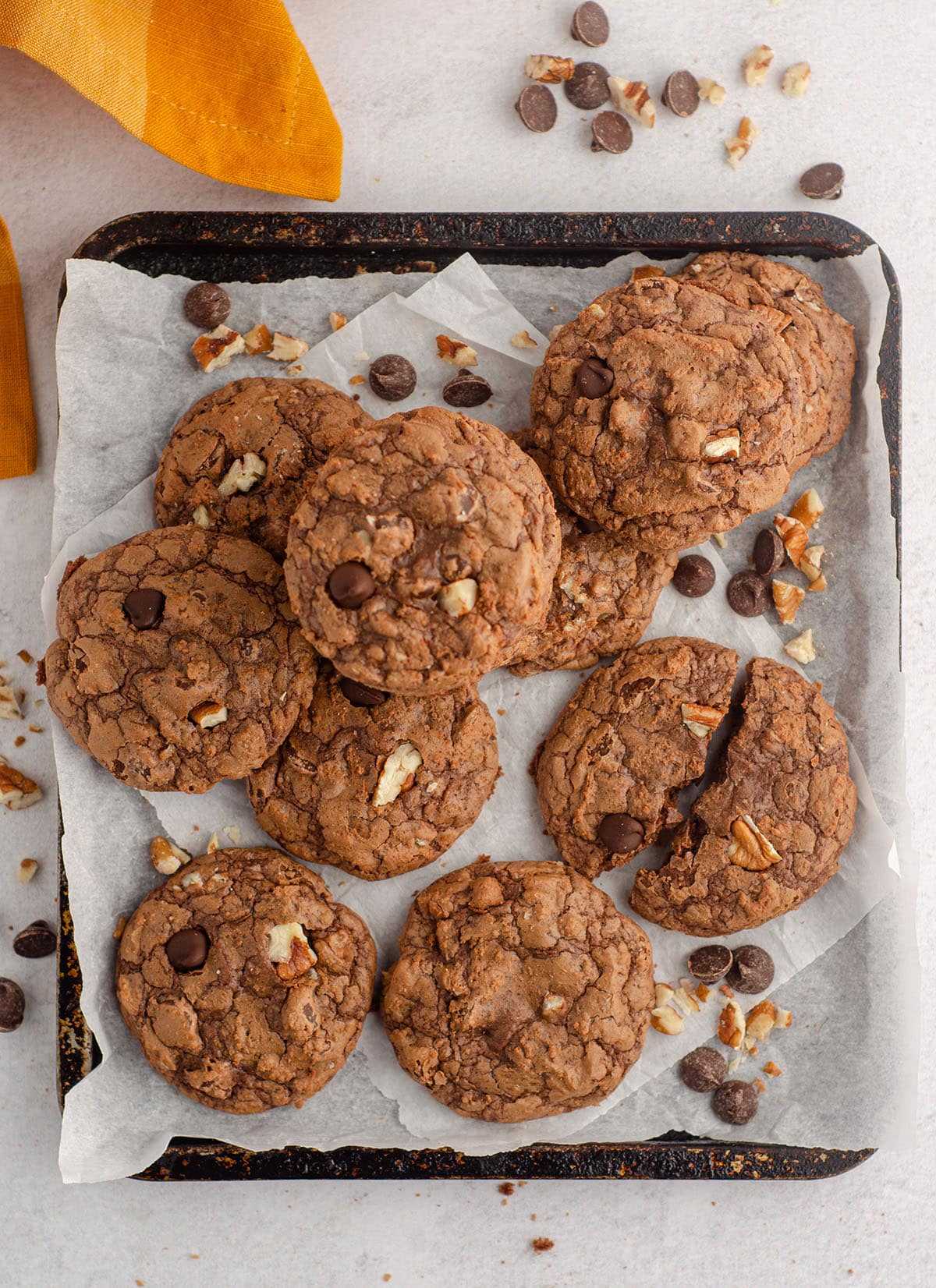 aerial photo of tray of brownie cookies with chocolate chips and nuts scattered around