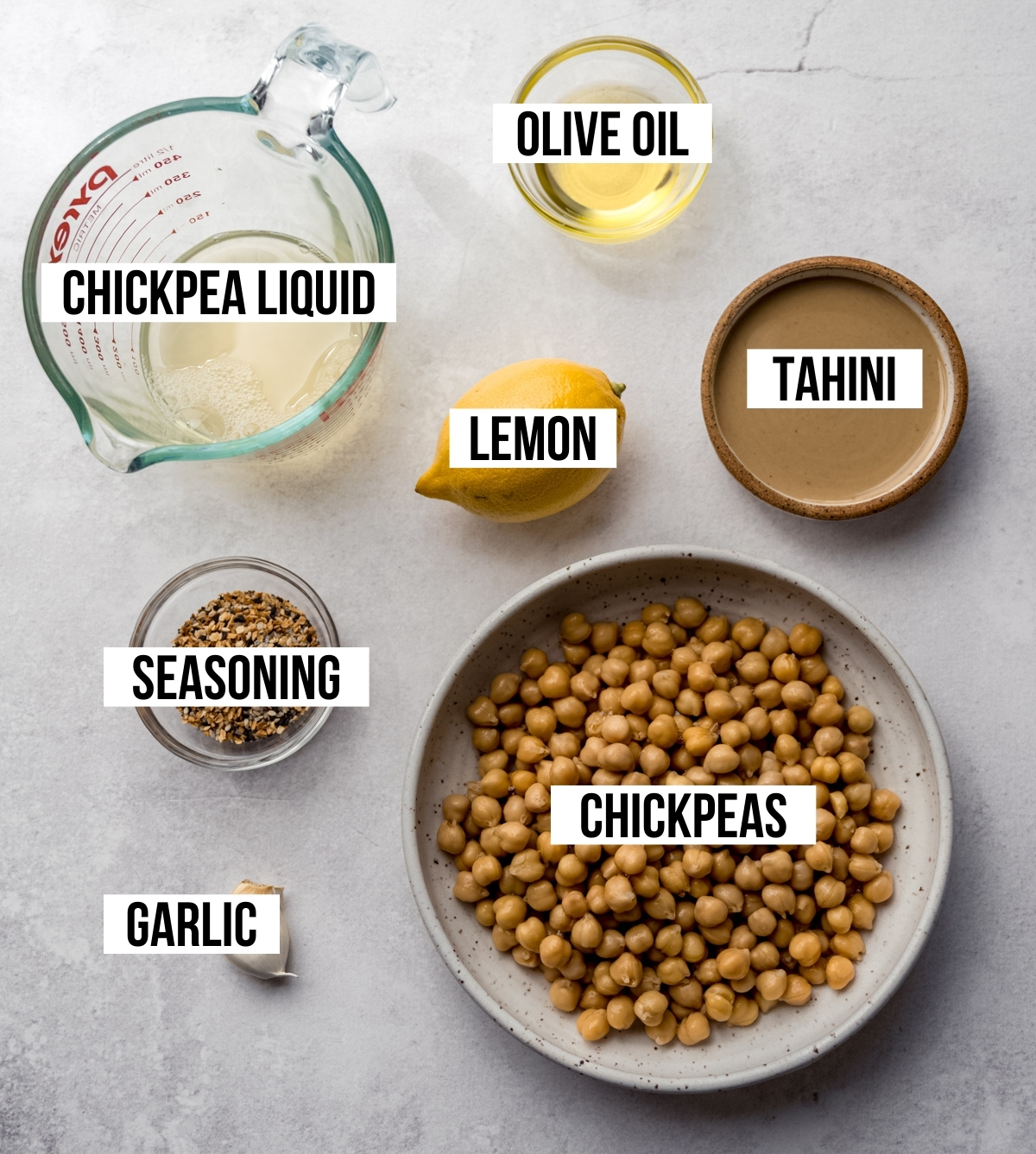 Aerial photo of ingredients to make everything bagel hummus with text overlay labeling each ingredient.