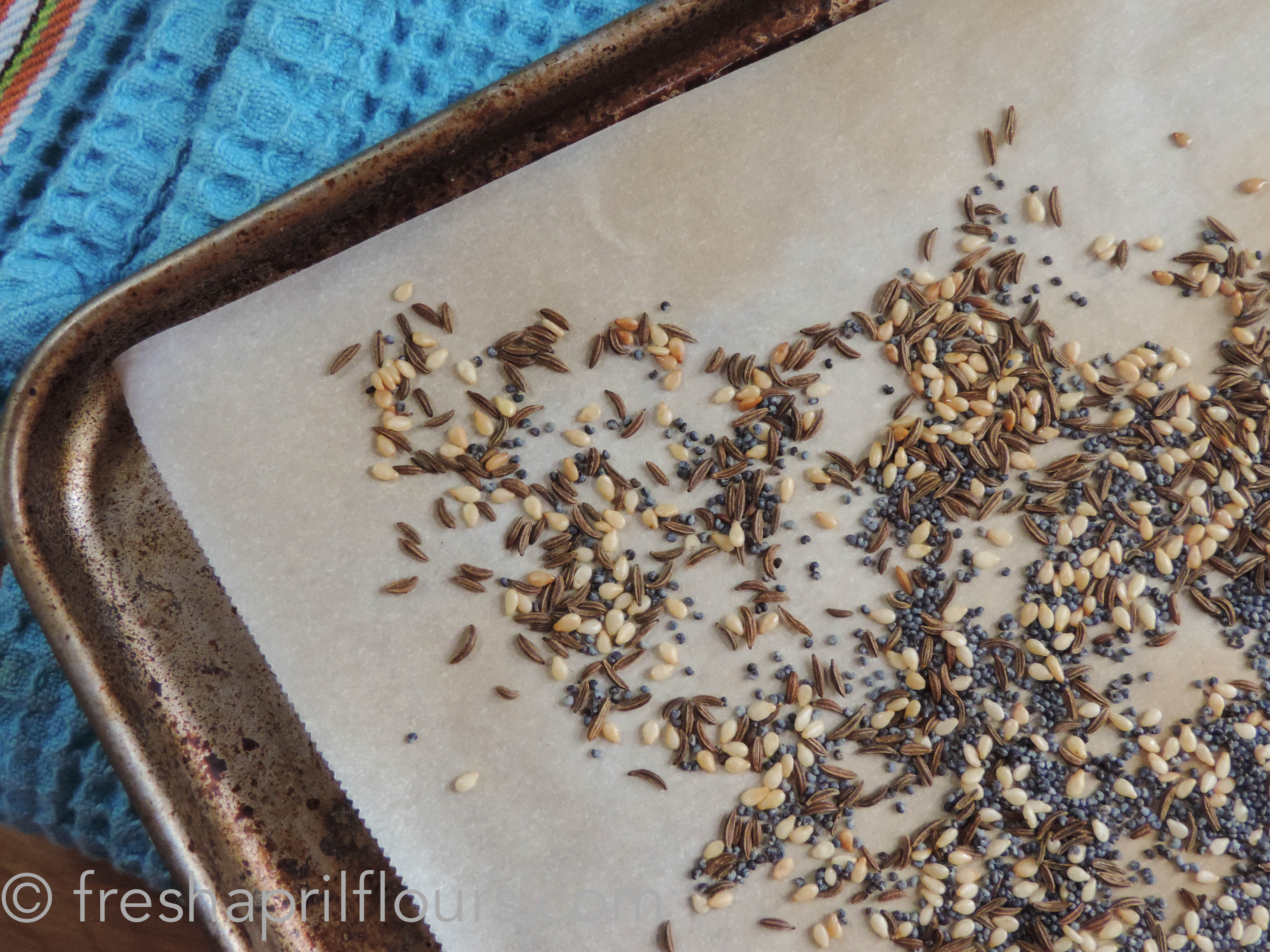 toasting seeds on a baking sheet for homemade everything bagel hummus