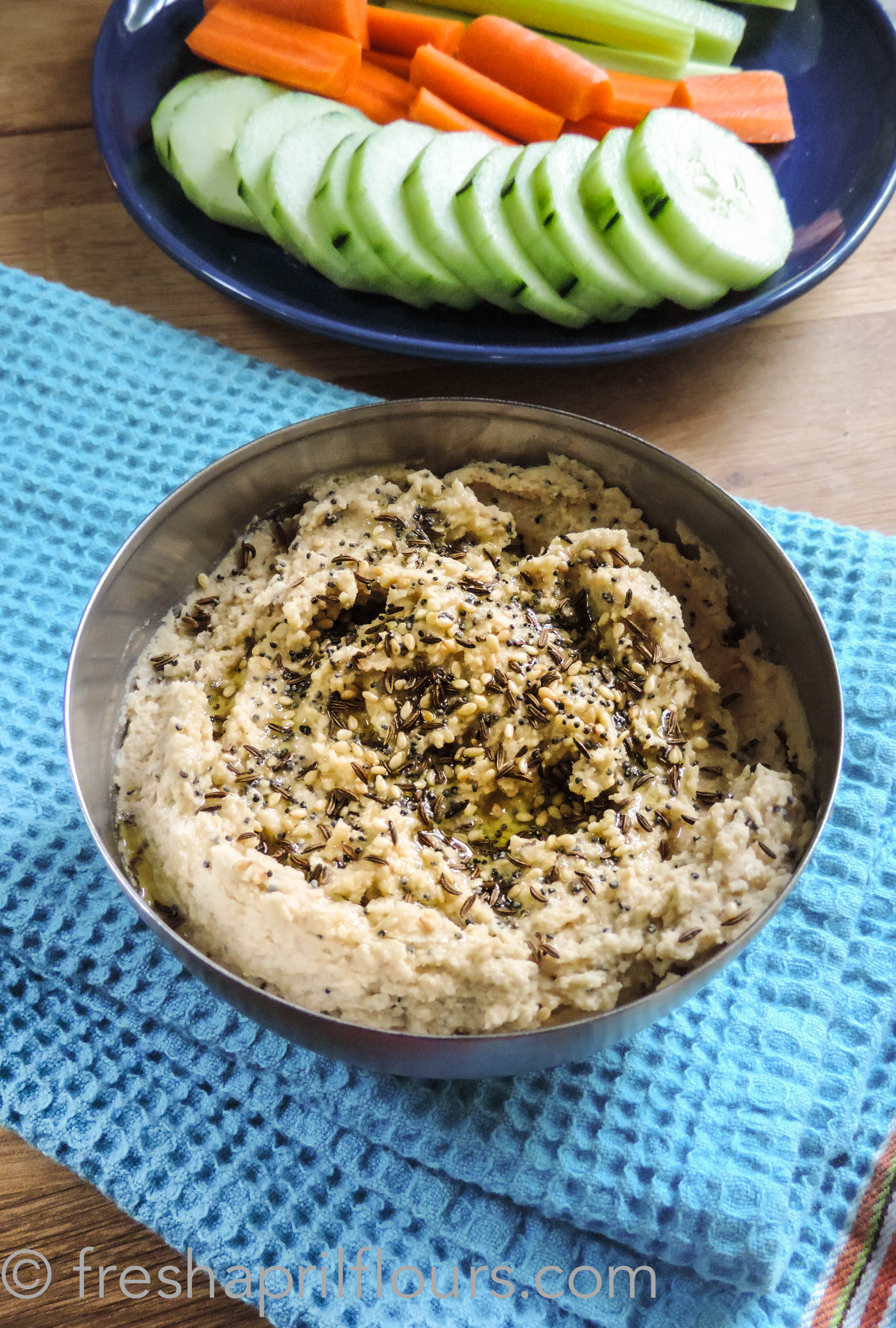 bowl of everything bagel hummus with veggies in the background