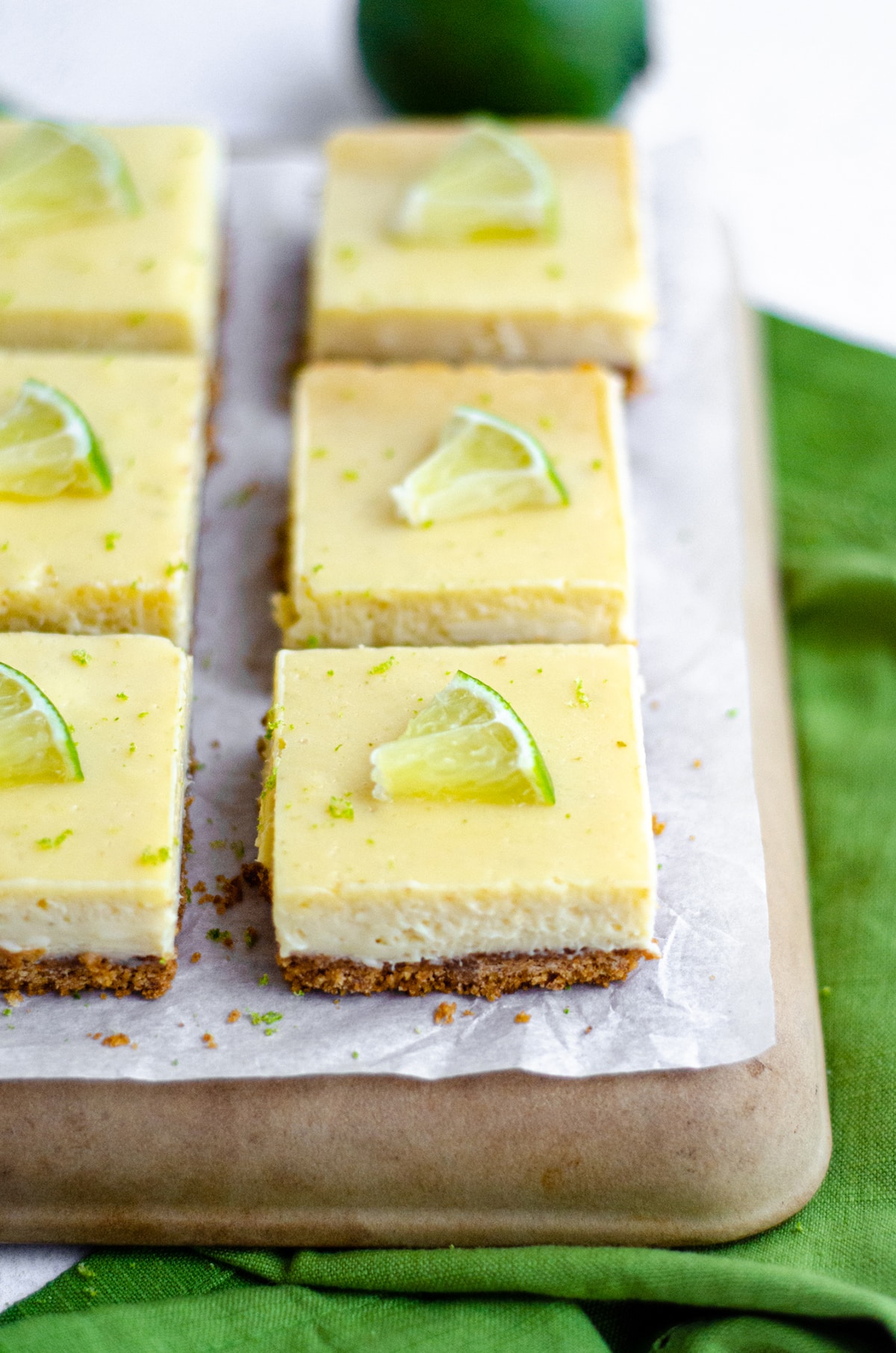 key lime pie bars on a platter and slices of lime on top of each