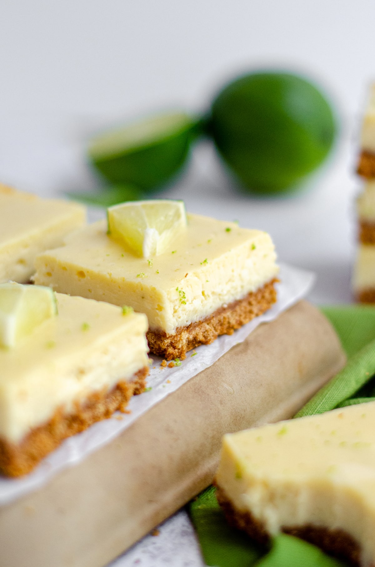 key lime pie bars on a platter with limes and slices of limes scattered around them