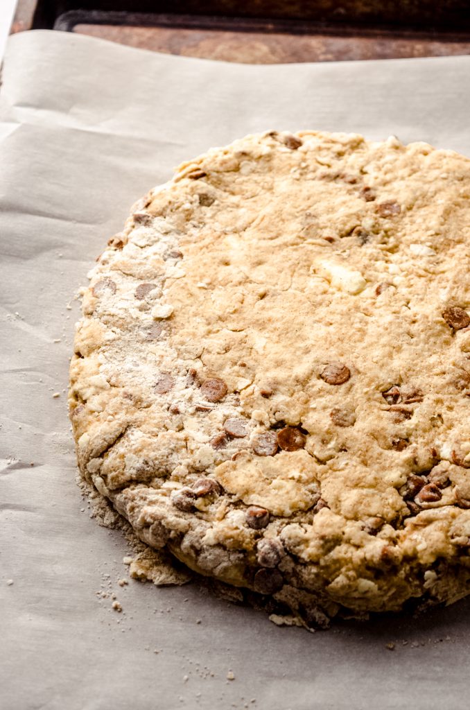 A disc of cinnamon scone dough on a piece of parchment.