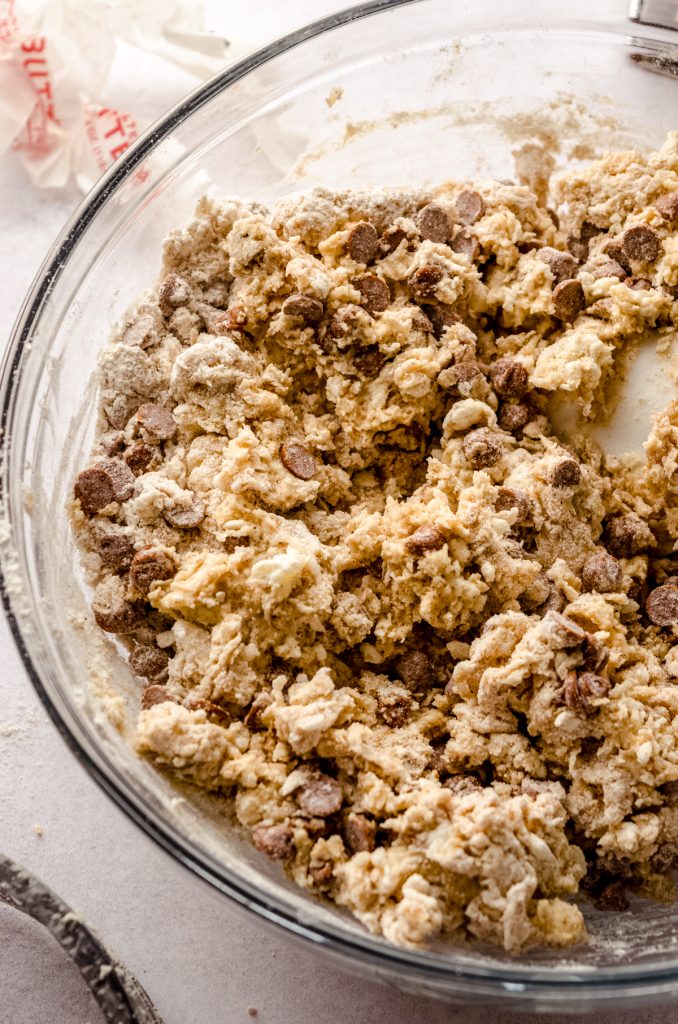 A bowl of cinnamon chip scone dough with a spatula in it.