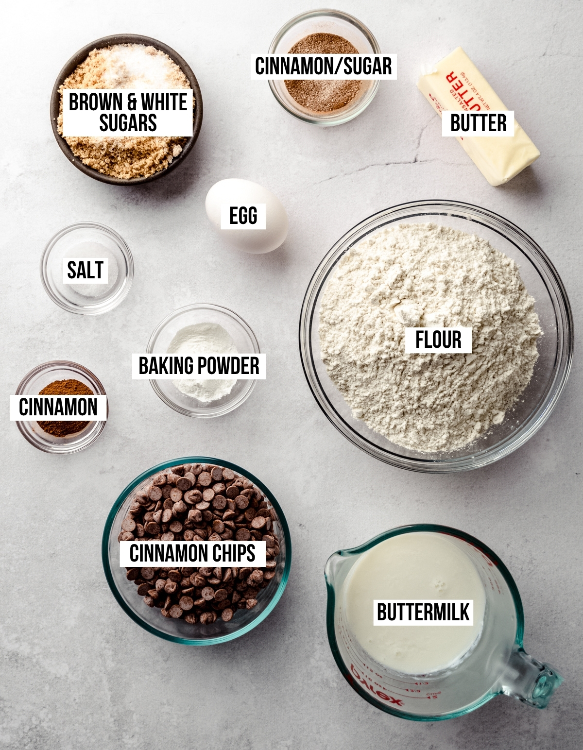 Aerial photo of ingredients to make cinnamon chip scones with text overlay labeling each ingredient.