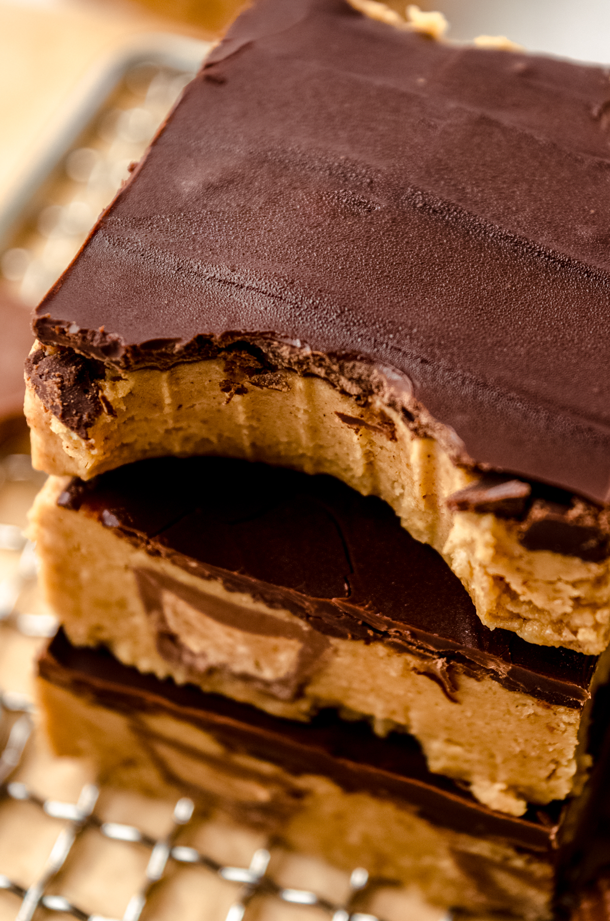 A closeup shot of a stack of peanut butter bars with a bite taken out of the one on the top.