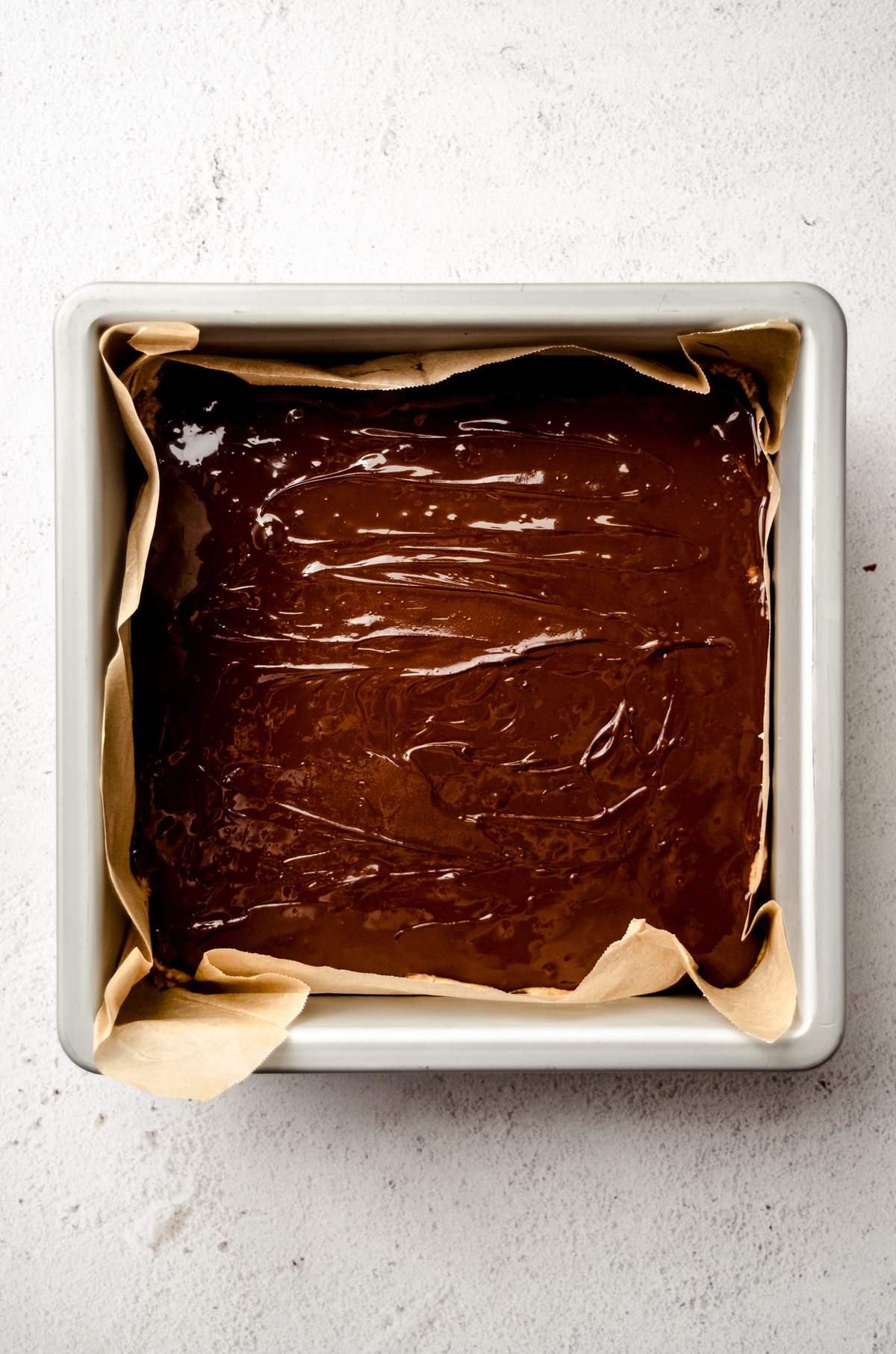 Aerial photo of chocolate spread on top of peanut butter bars in a pan.