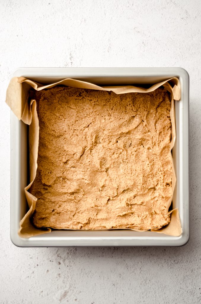 Aerial photo of the top layer of peanut butter filling pressed into a baking pan to make peanut butter bars.