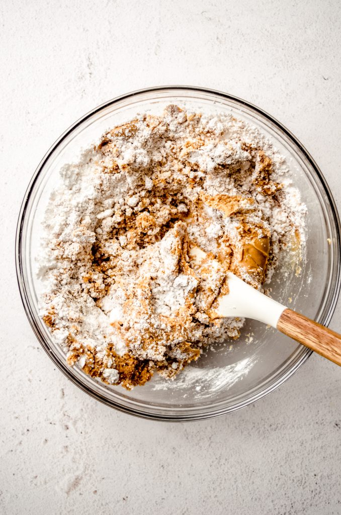 Aerial photo of a bowl of ingredients being mixed together to make peanut butter bars with a spatula in the bowl.