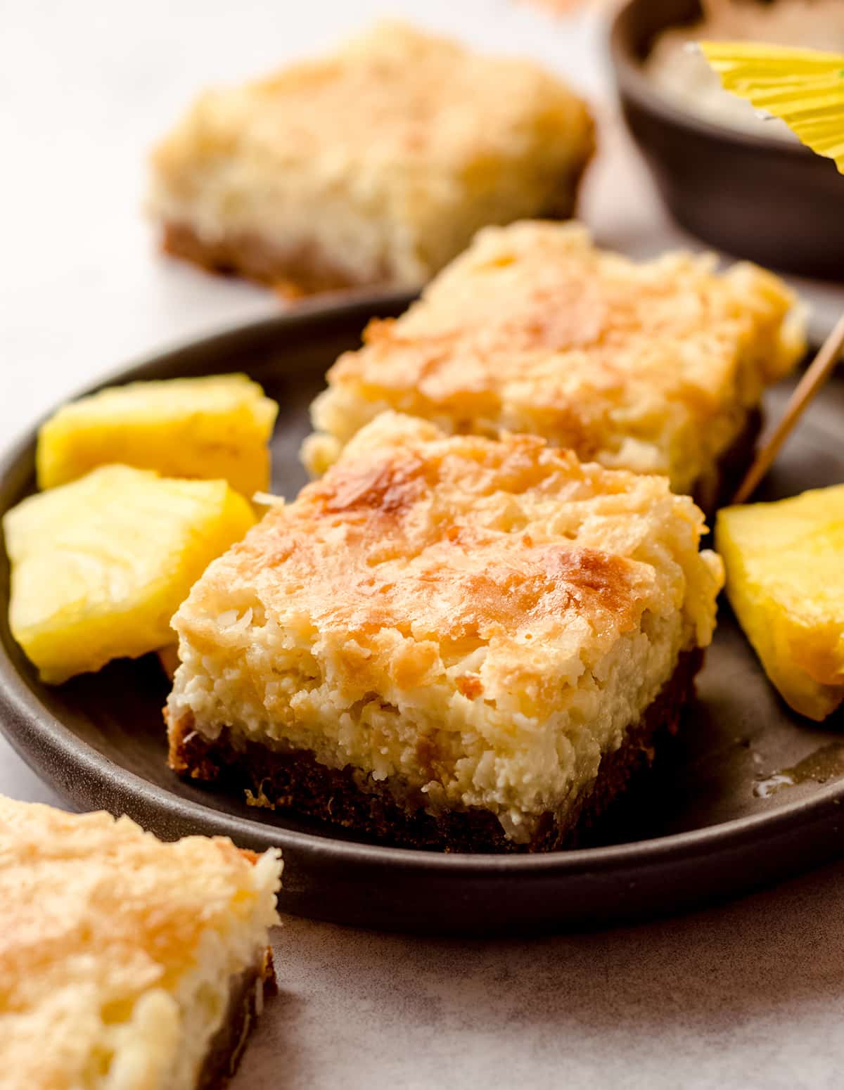 piña colada bars on a plate with pineapple chunks