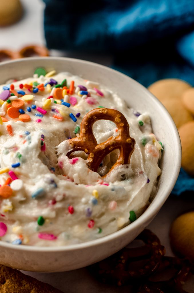cake batter dip in a bowl with a pretzel stuck in it