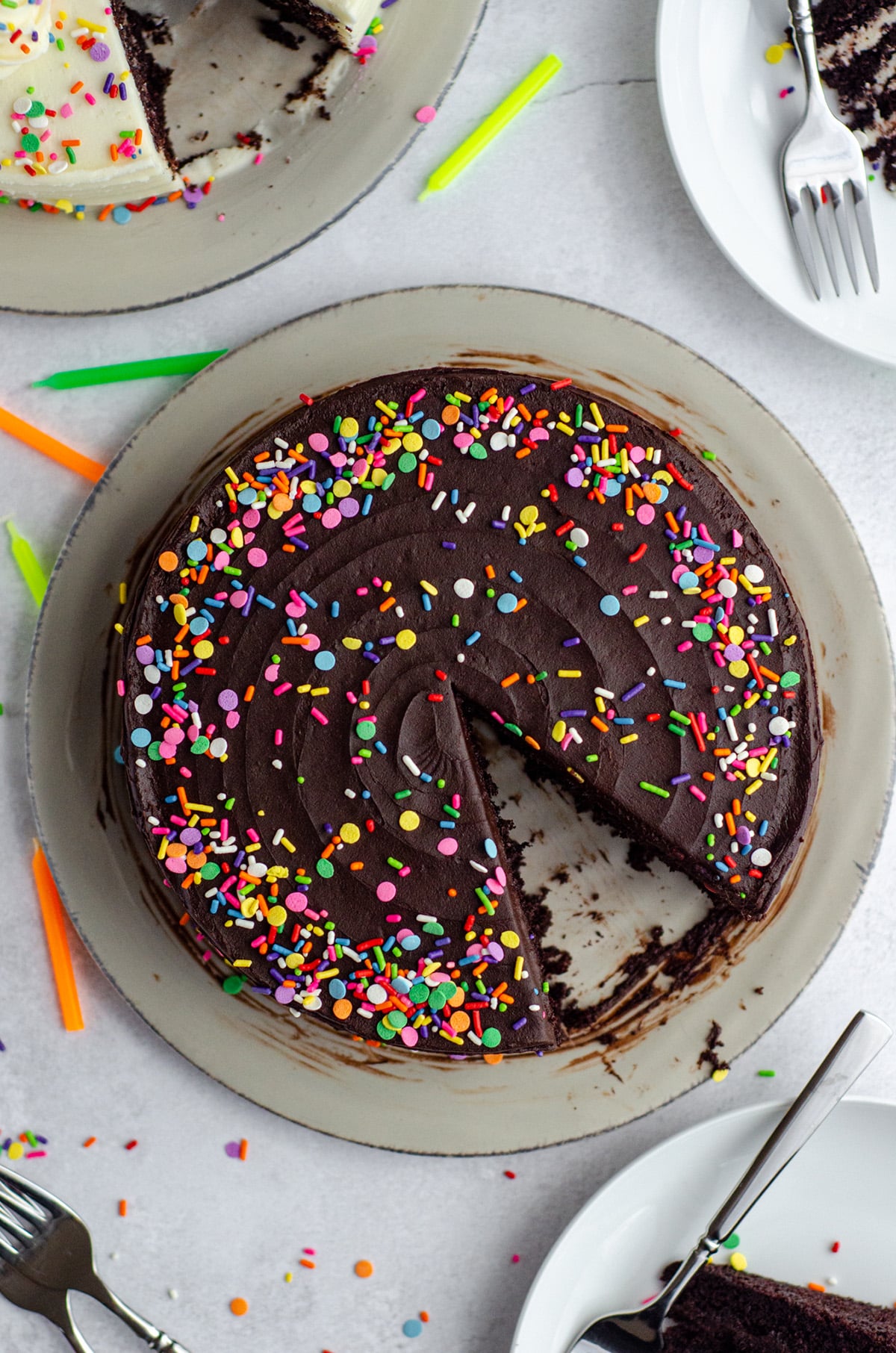 aerial photo of chocolate layer cake with chocolate buttercream and rainbow sprinkles with a slice taken out of it