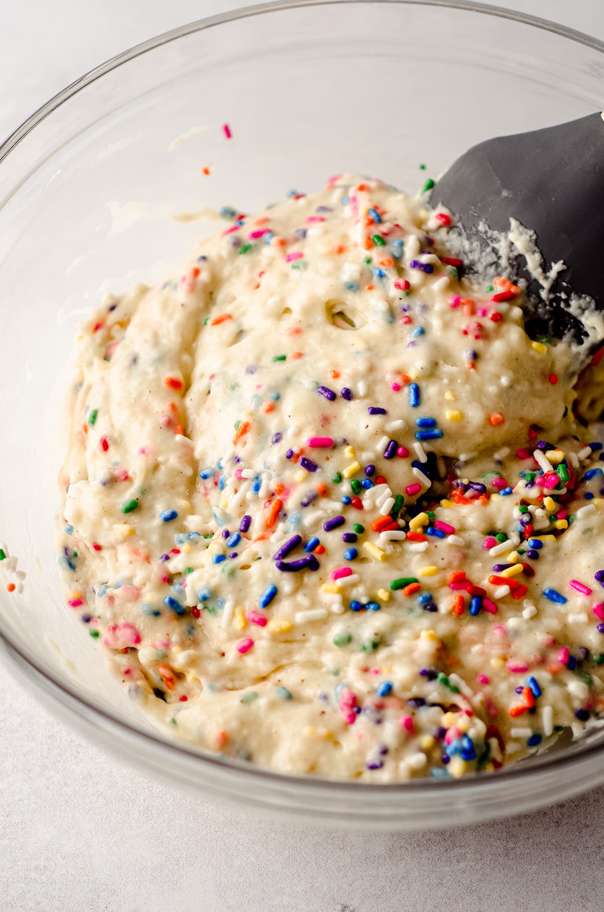 funfetti donut batter in a glass bowl with a spatula