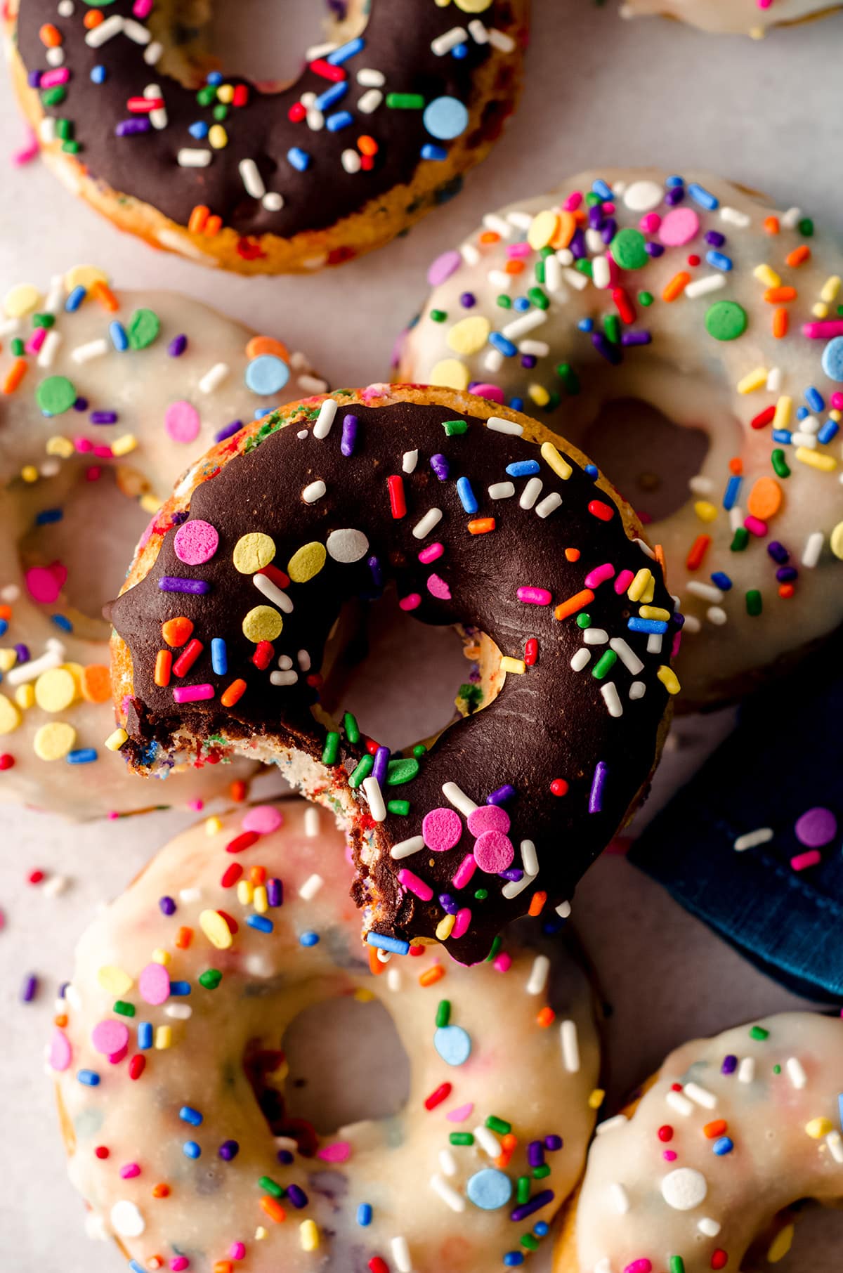 aerial photo of a stack of funfetti donuts and the one on the top has a bite taken out of it