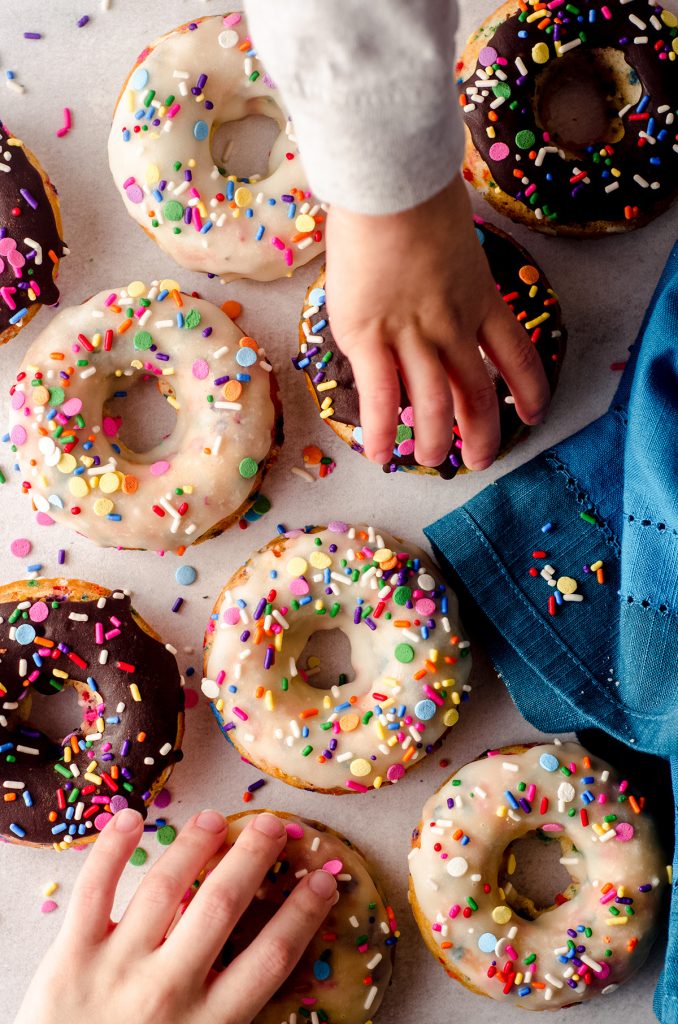 aerial photo of children's hands grabbing funfetti donuts