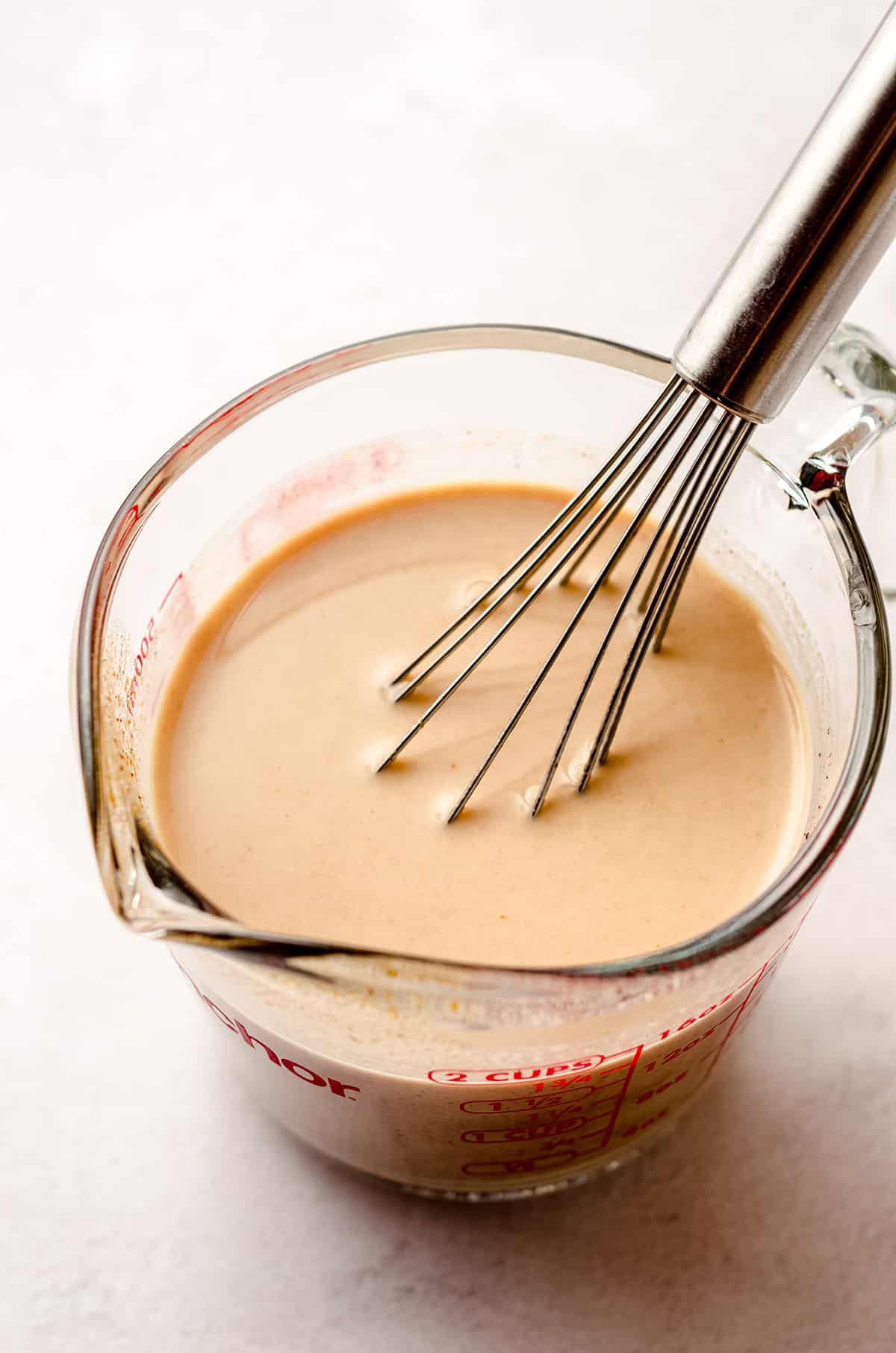 homemade pumpkin coffee creamer in a glass measuring cup with a whisk