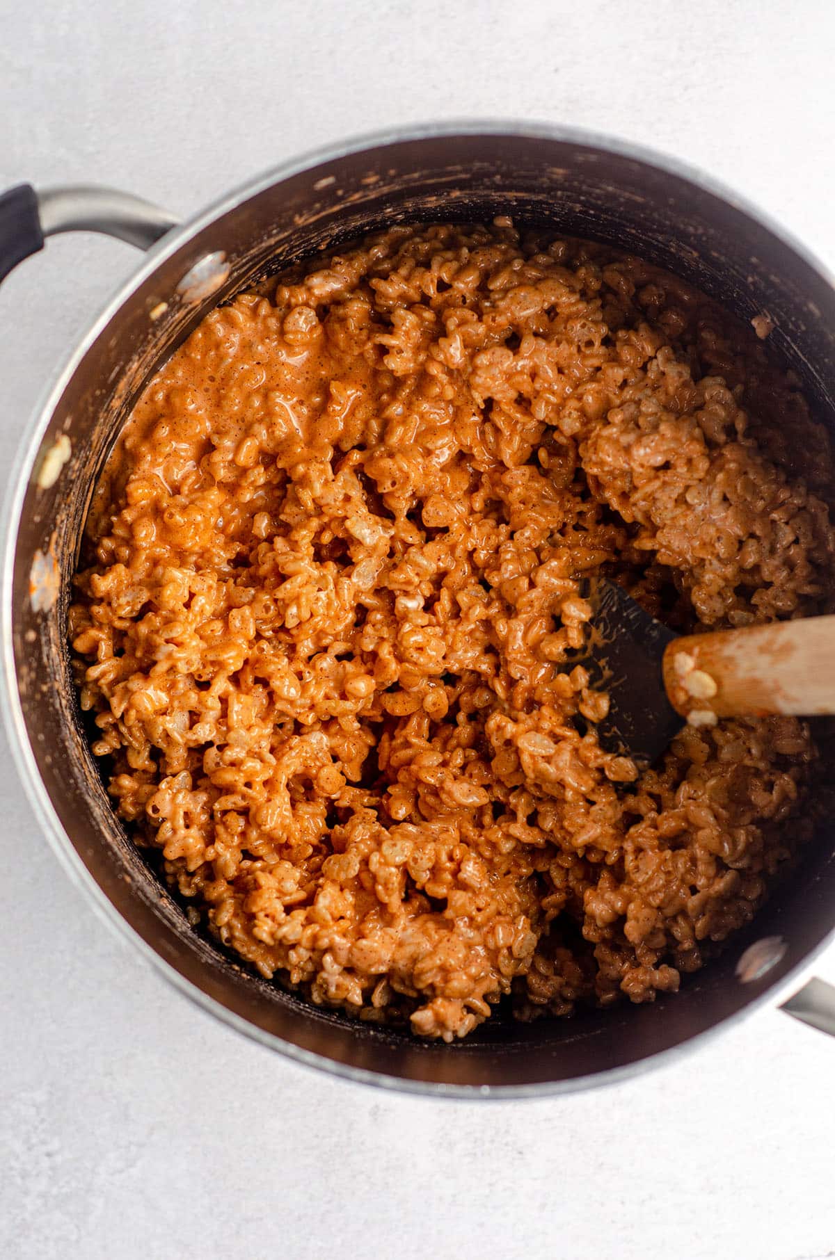 orange rice krispies treats in a pot ready to be pressed into pan
