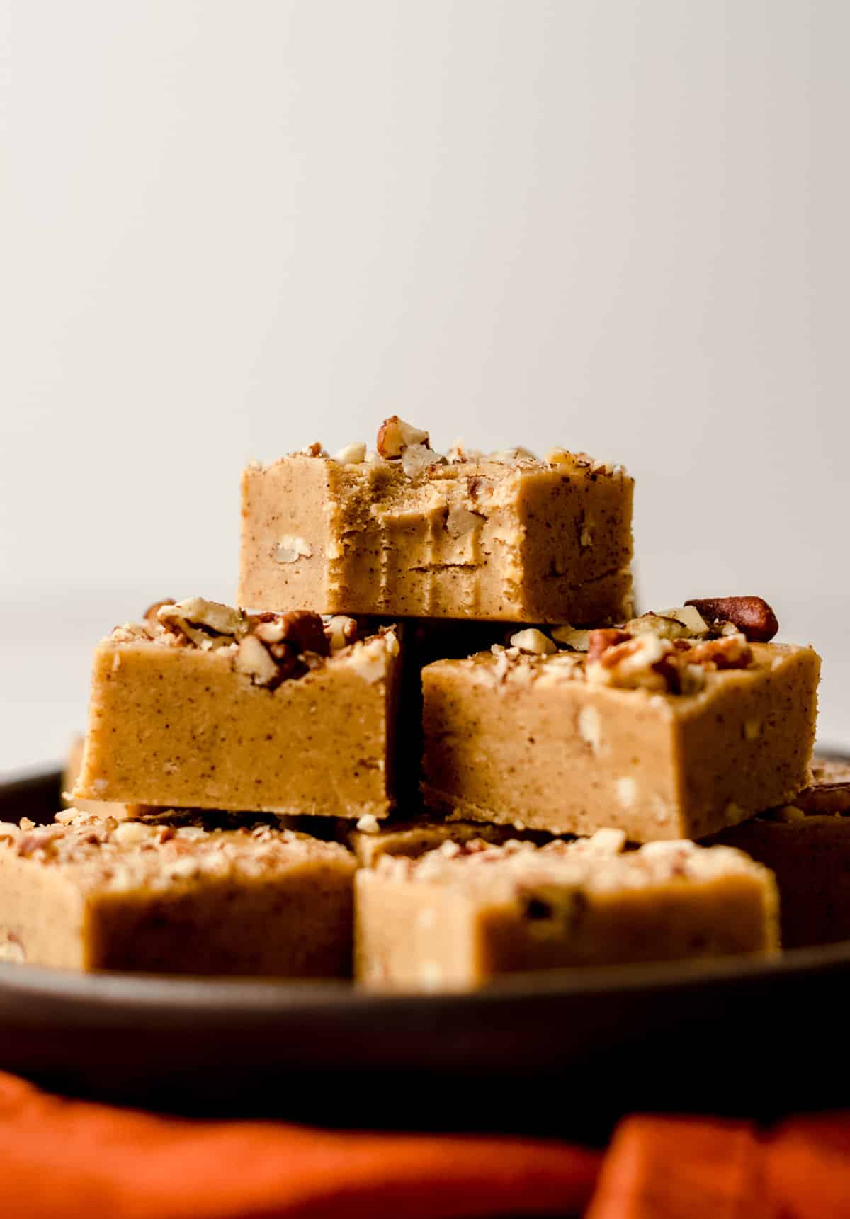 pumpkin fudge pieces on a plate with a bite taken out of the one on the top