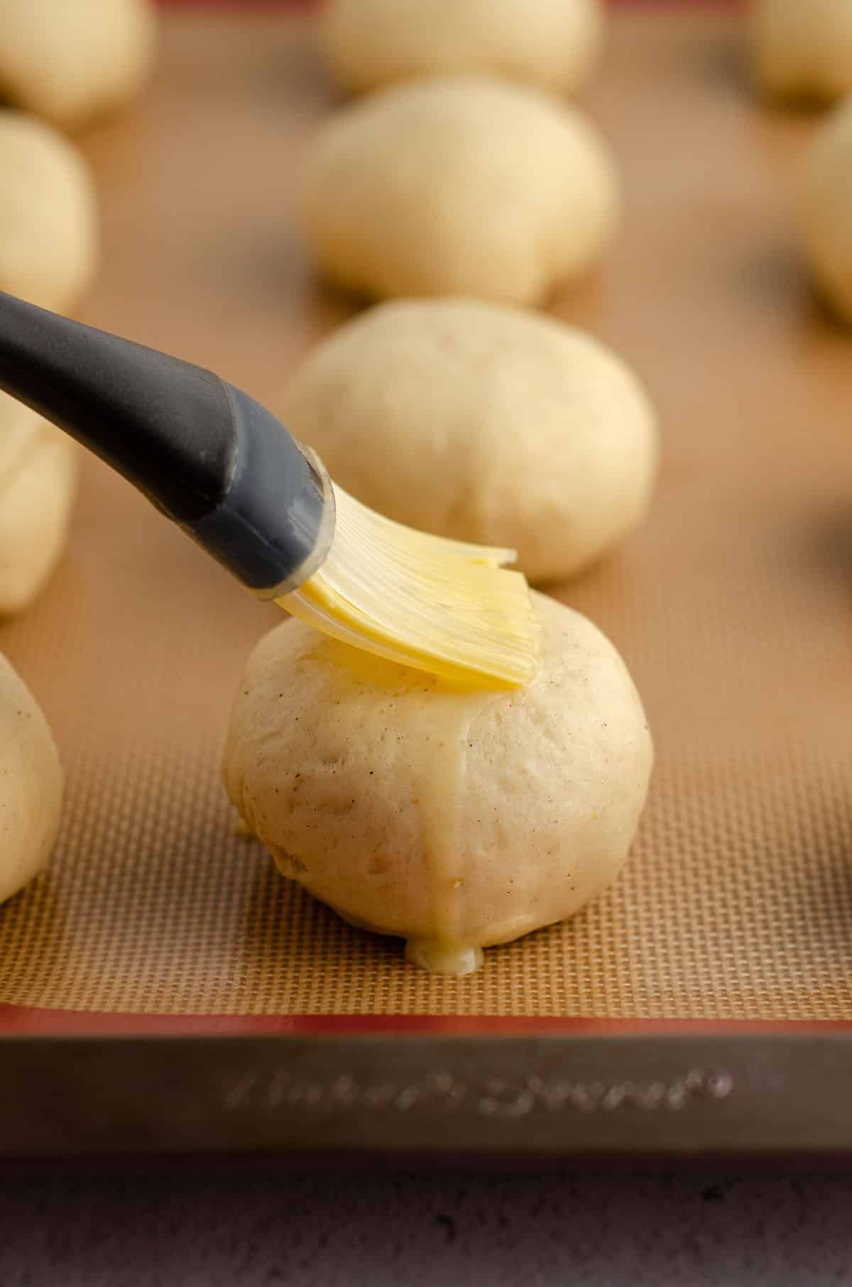 brushing rolls with a pastry brush and an egg wash