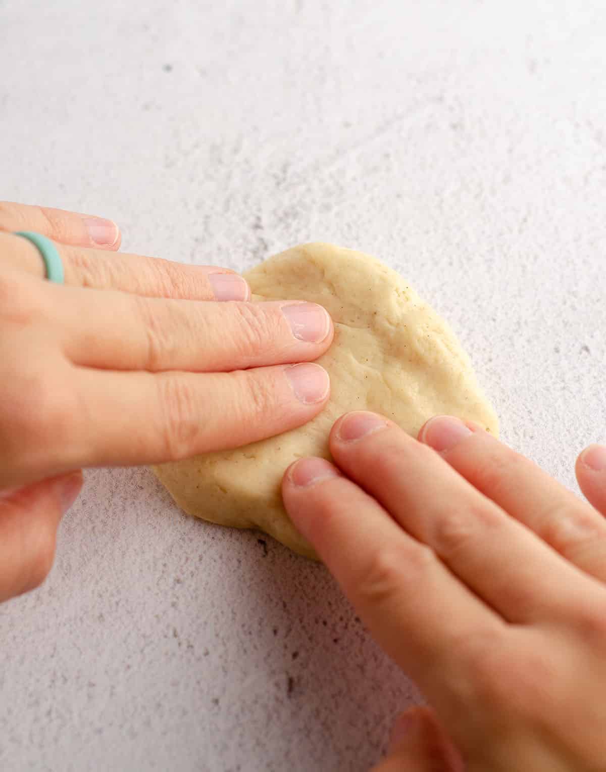 hands forming bread dough into a disc