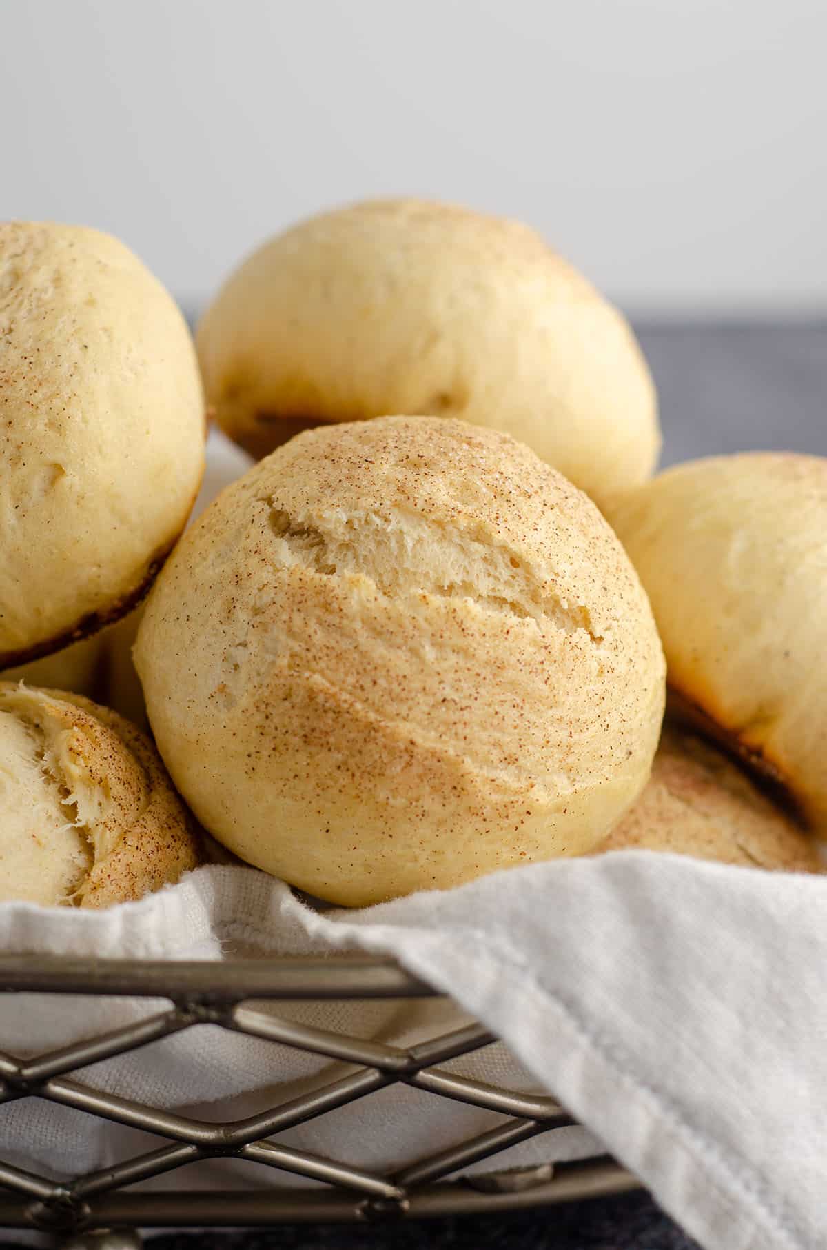 cardamom rolls sitting in a basket with a white kitchen cloth