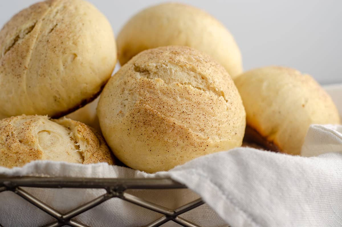 cardamom rolls sitting in a basket with a white kitchen cloth