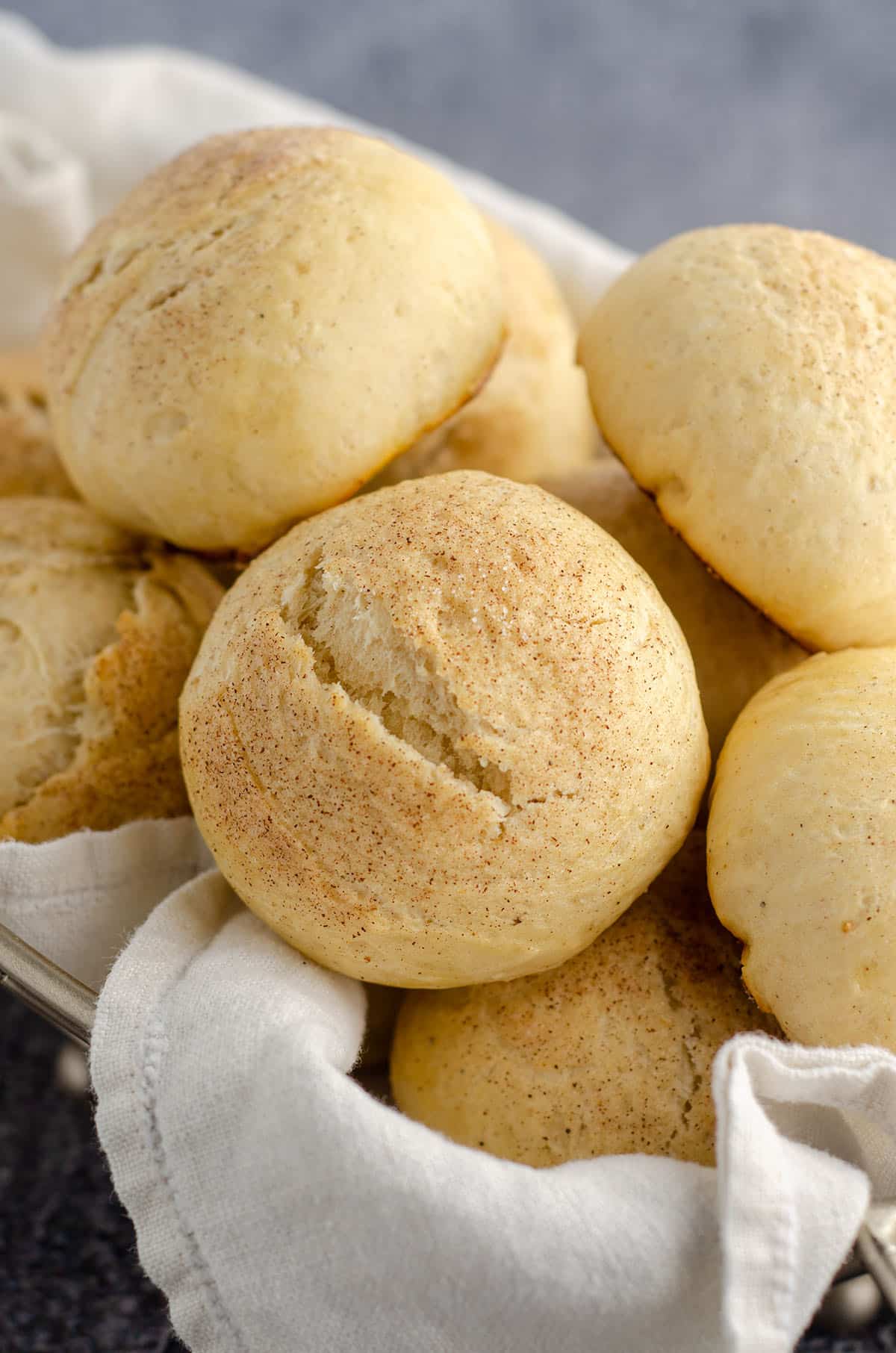 cardamom rolls sitting in a basket with a white kitchen cloth