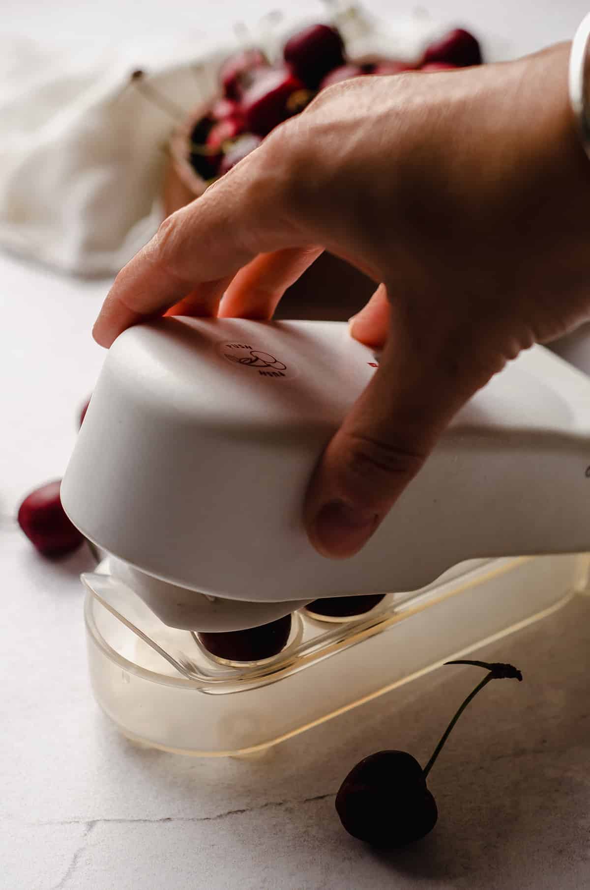 hand pushing the handle on a cherry pitter