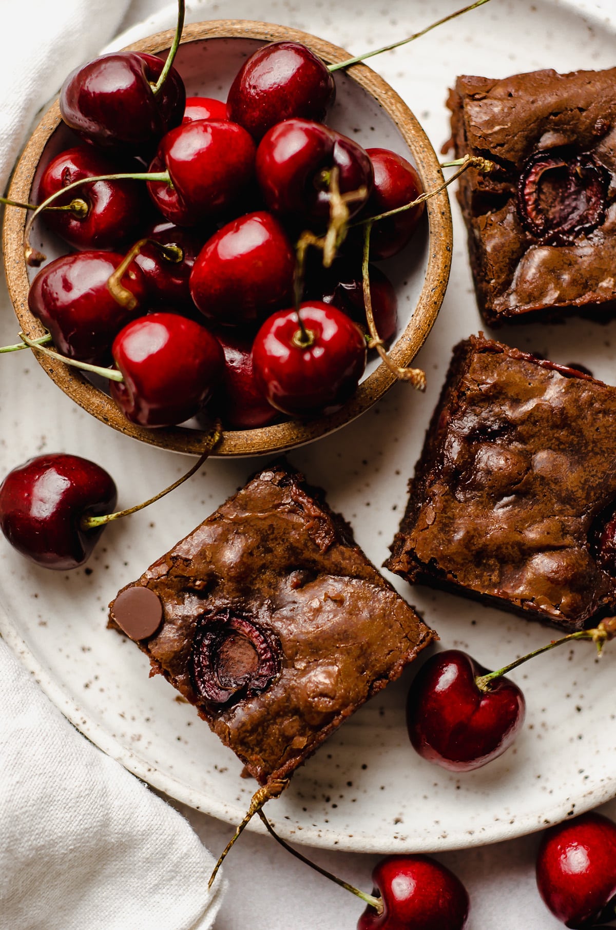 aerial photo of cherry brownies on a plate with a bowl of cherries