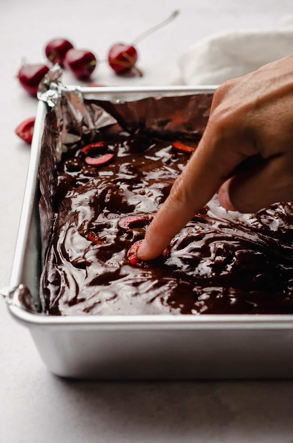 pressing a cherry into cherry brownie batter