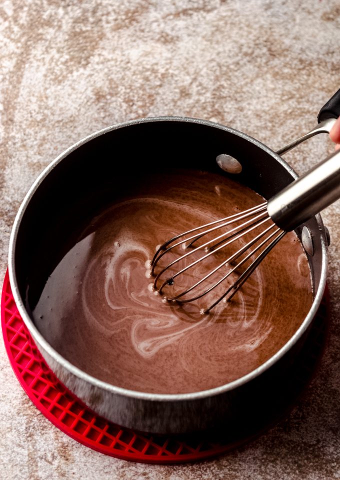 A saucepan of homemade peppermint mocha coffee creamer that someone is whisking together.