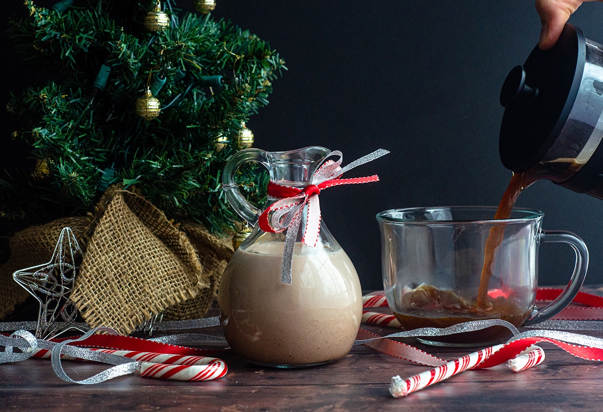 peppermint mocha coffee creamer in a pourer and someone pouring coffee into a cup in the background