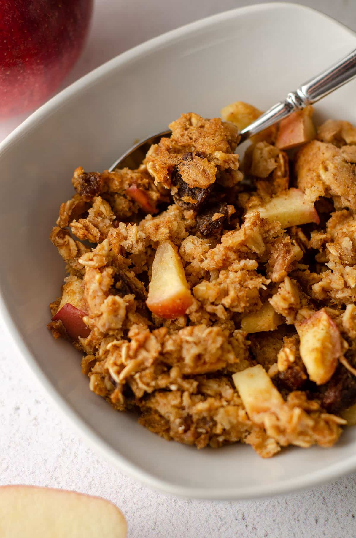 baked apple oatmeal in a white bowl with a spoon