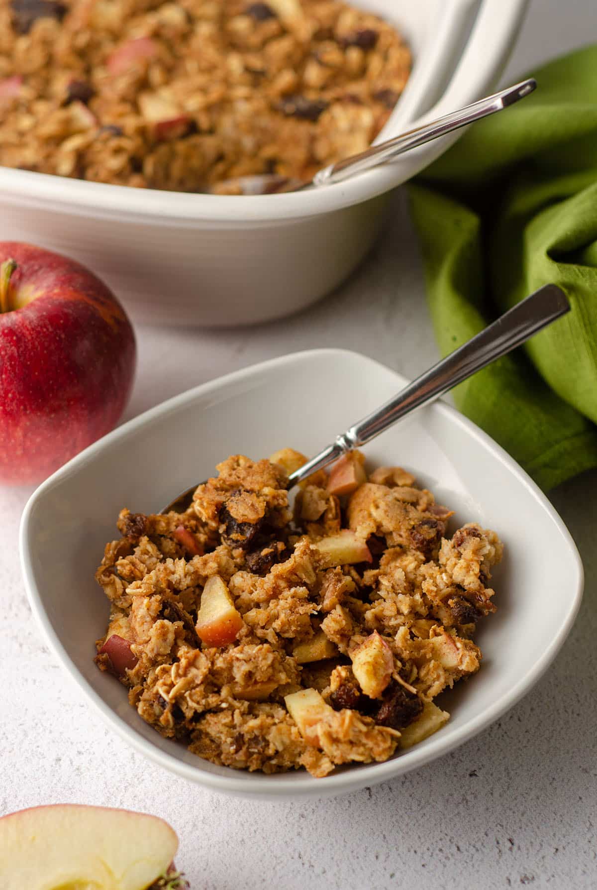 baked apple oatmeal in a white bowl with a spoon