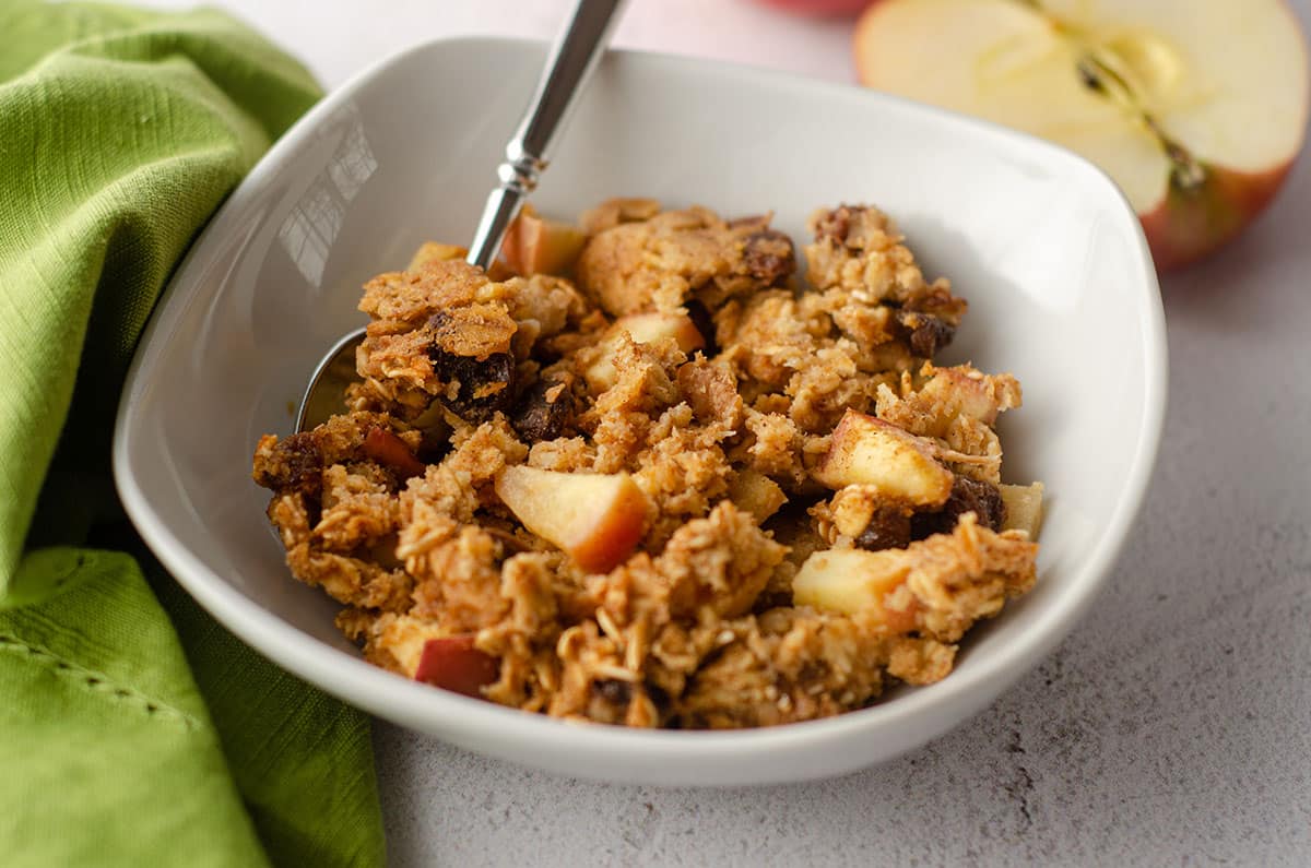 baked apple oatmeal in a white bowl with a spoon