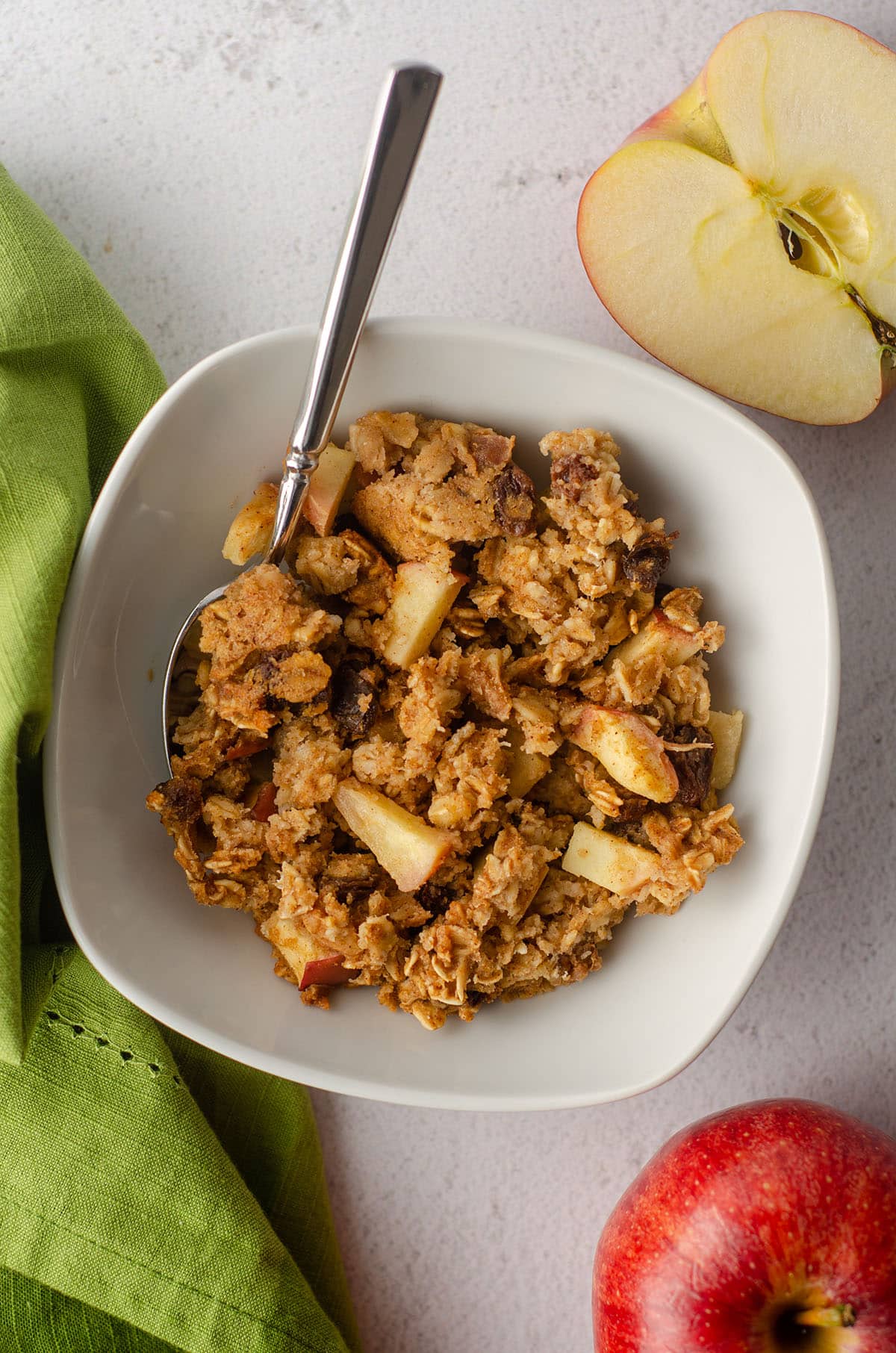 aerial photo of baked apple oatmeal in a white bowl with a spoon