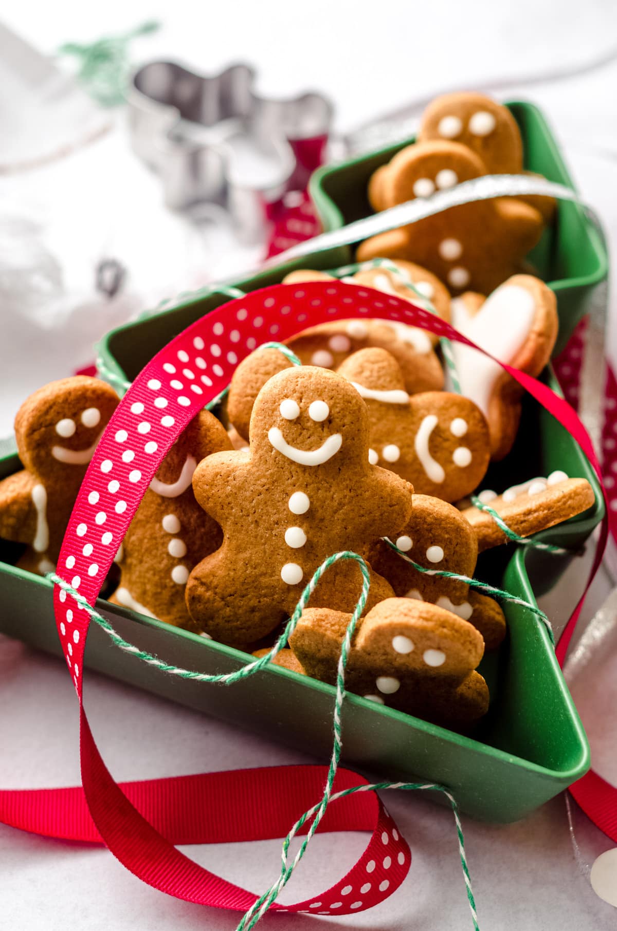 gingerbread cut-out cookies in a christmas tree tin with ribbons all around