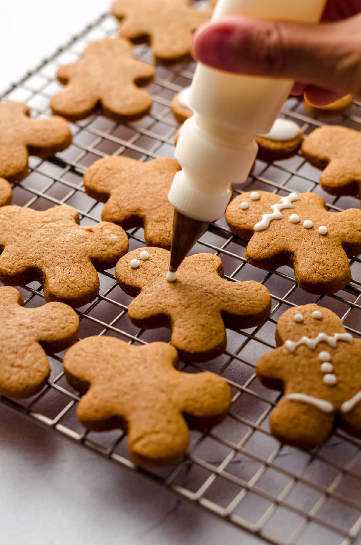 hand decorating a gingerbread cut-out cookie with royal icing