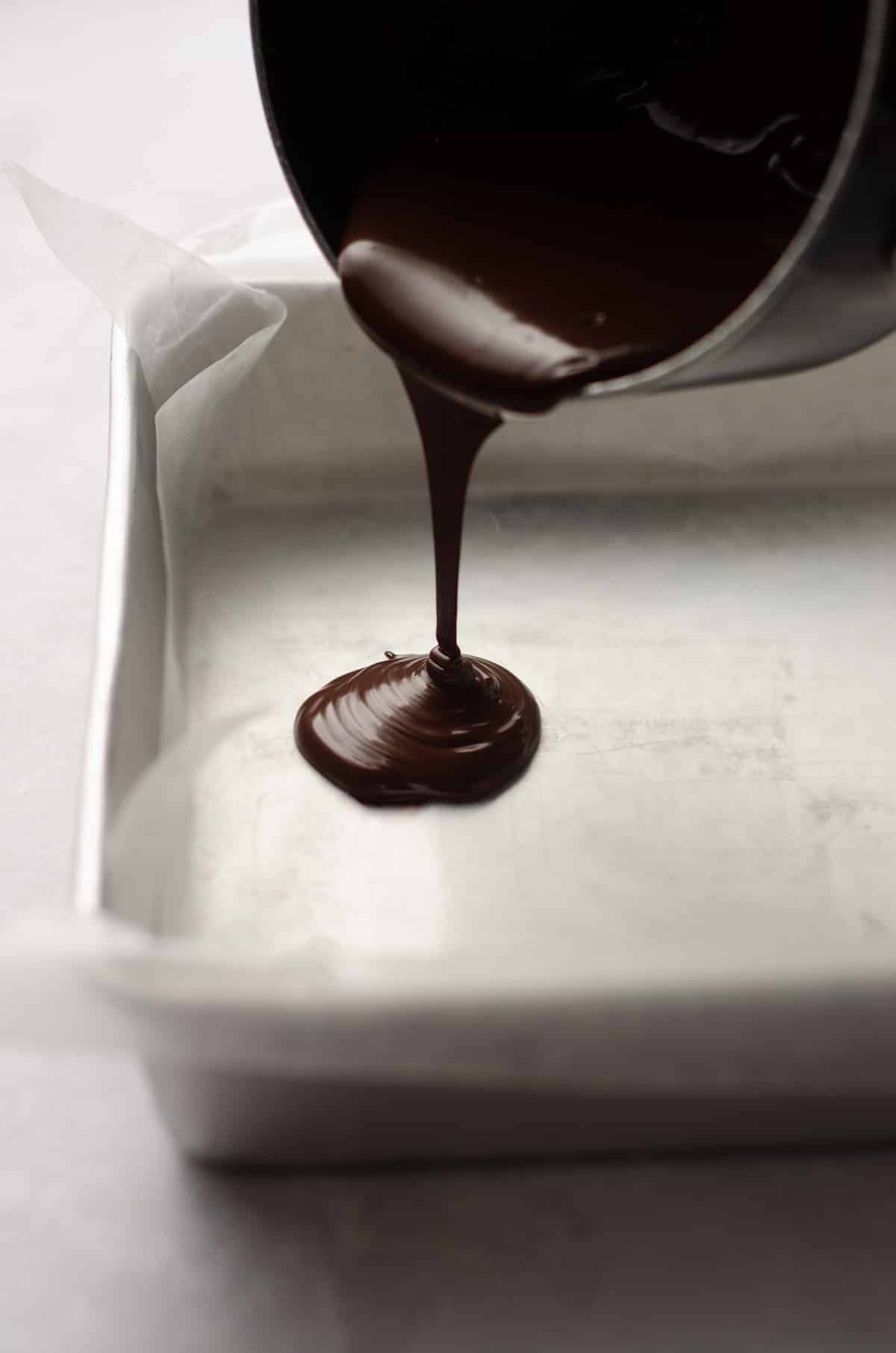 pouring semi-sweet chocolate into a pan for peppermint bark