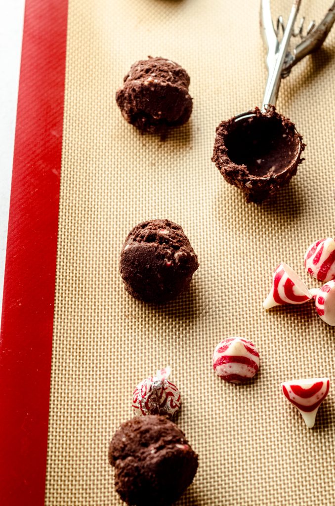 Chocolate peppermint blossom cookie dough balls on a baking sheet.