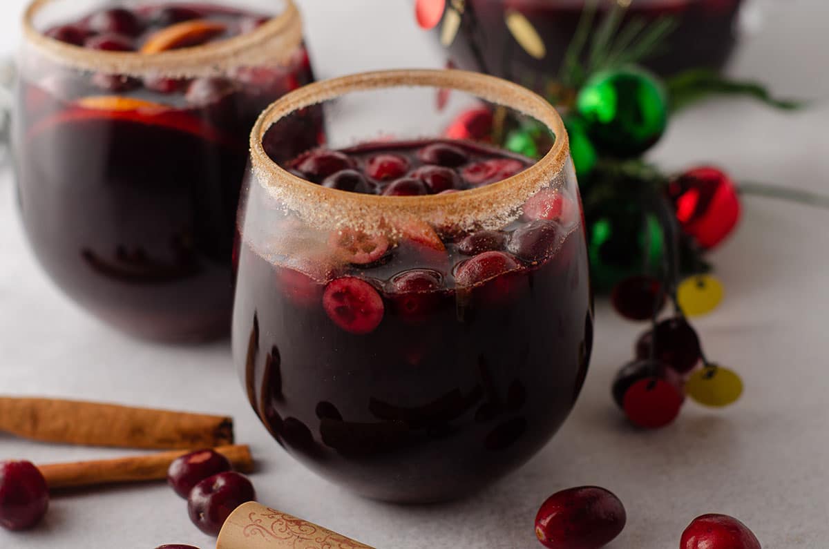 cranberry and orange winter sangria sitting in a glass with a cinnamon sugared rim