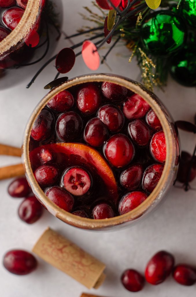 aerial photo of cranberry and orange winter sangria sitting in a glass with a cinnamon sugared rim